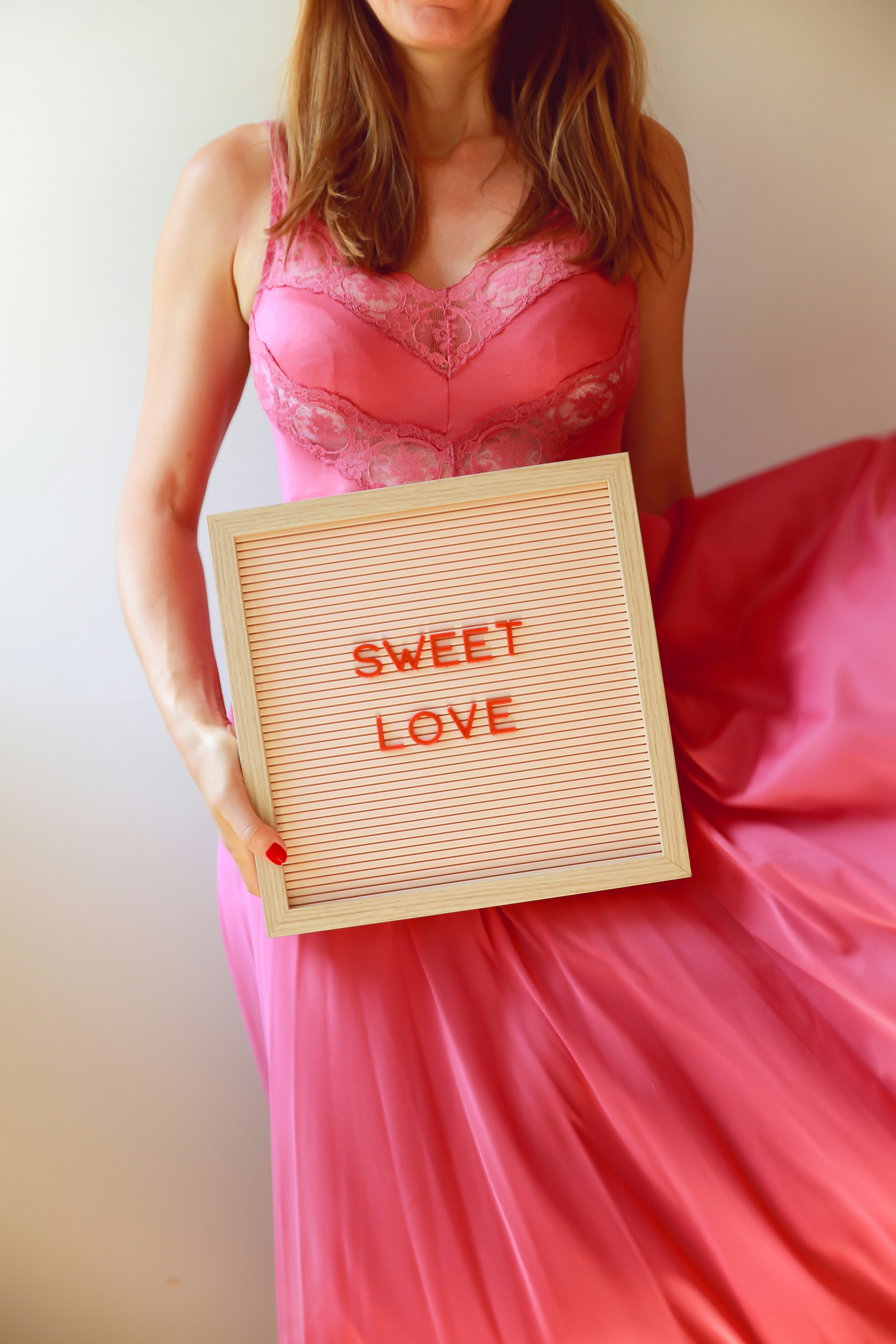 Woman in pink dress holds a sign: "sweet love".
