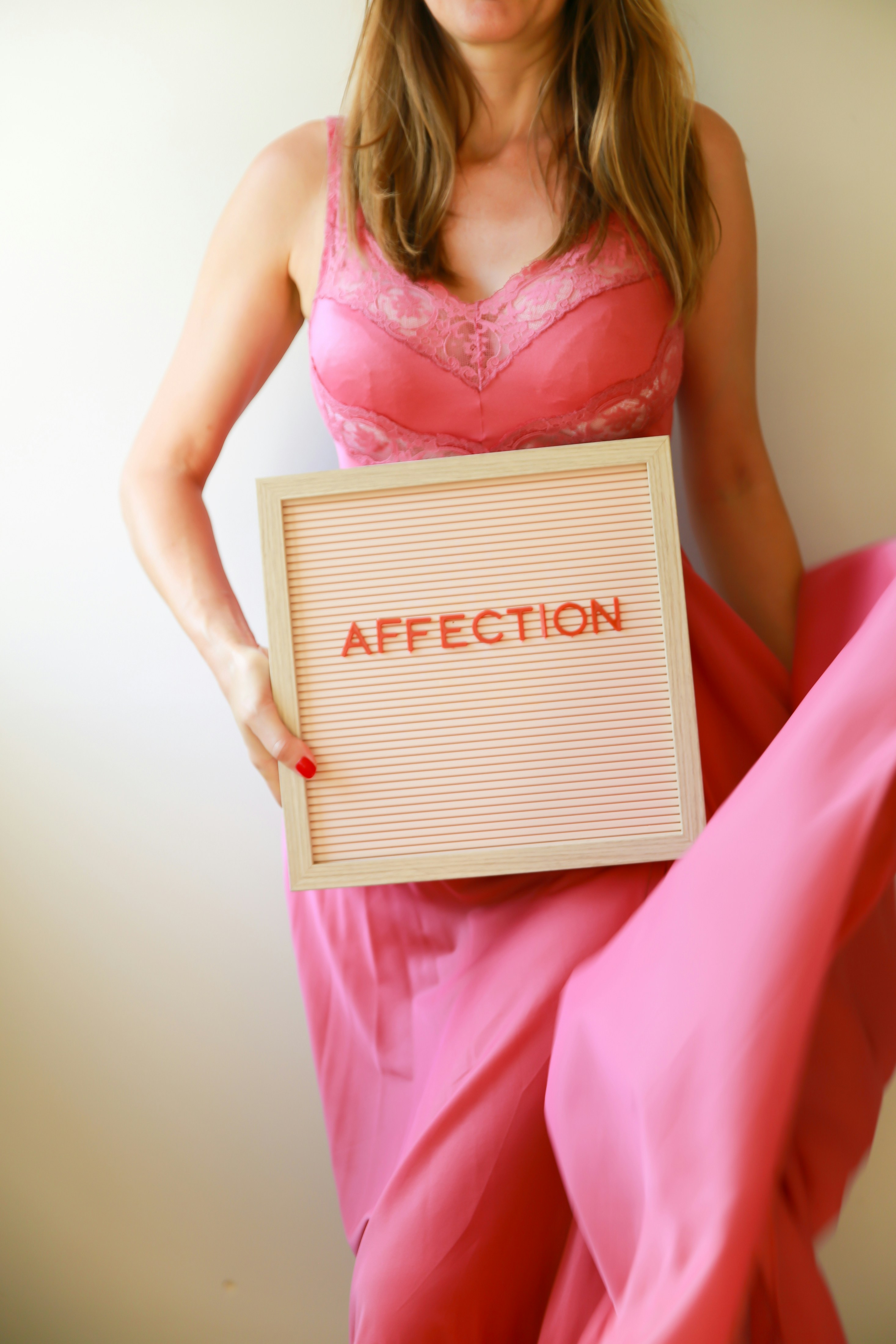 Kvinde i lyserød holder et skilt med "kærlighed".