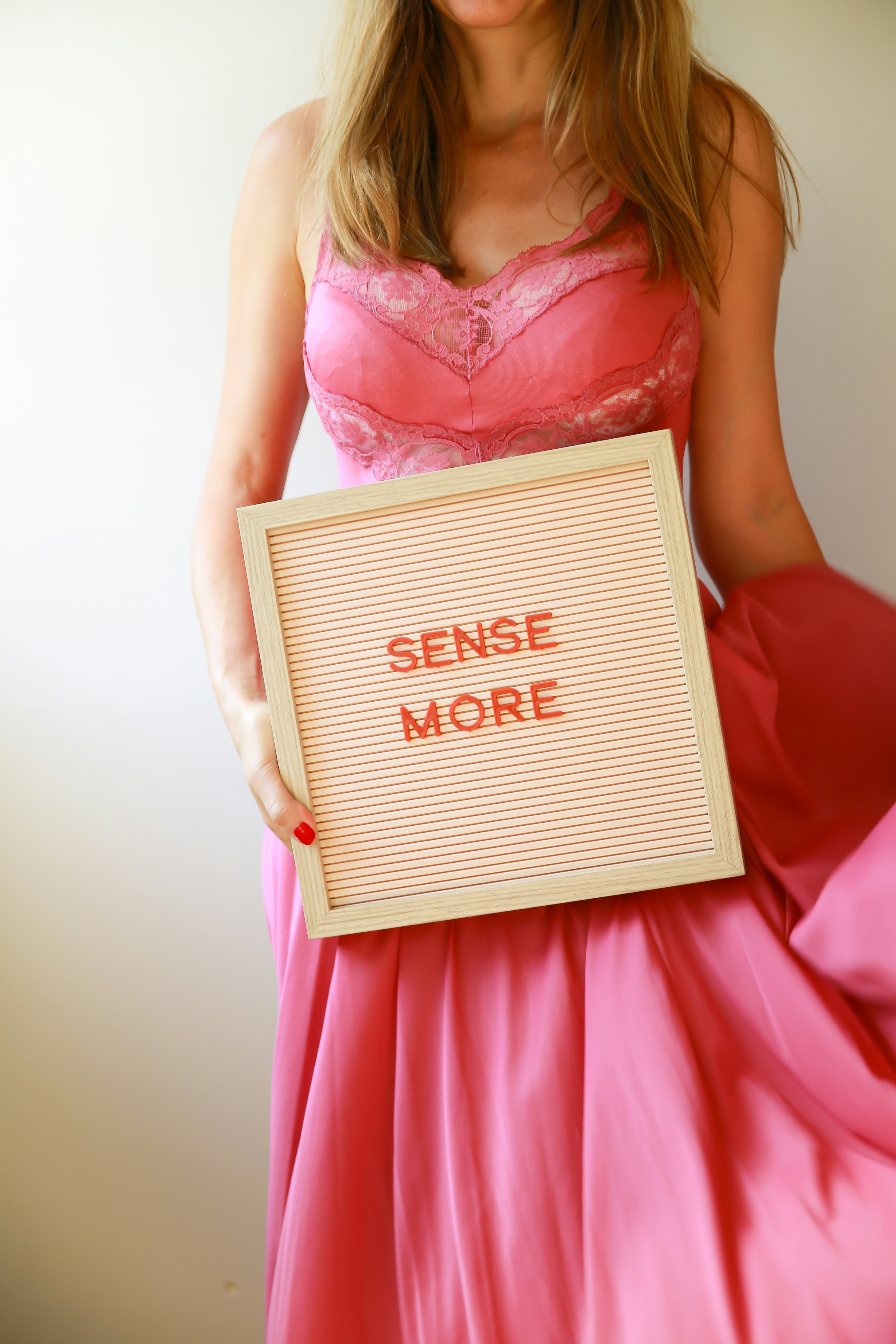 Woman holds a sign that says "sense more".
