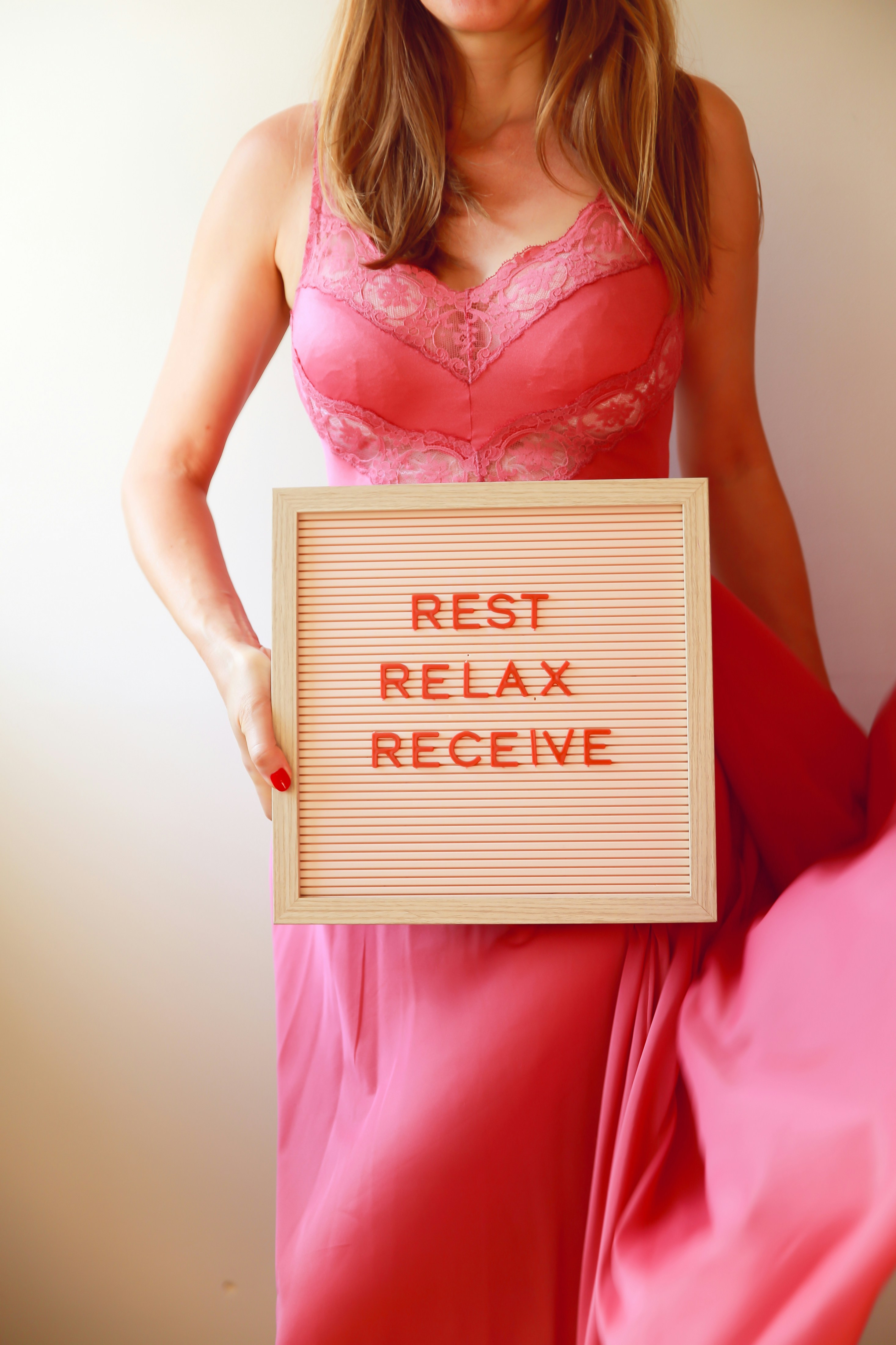 Woman holds a sign: "rest, relax, receive."