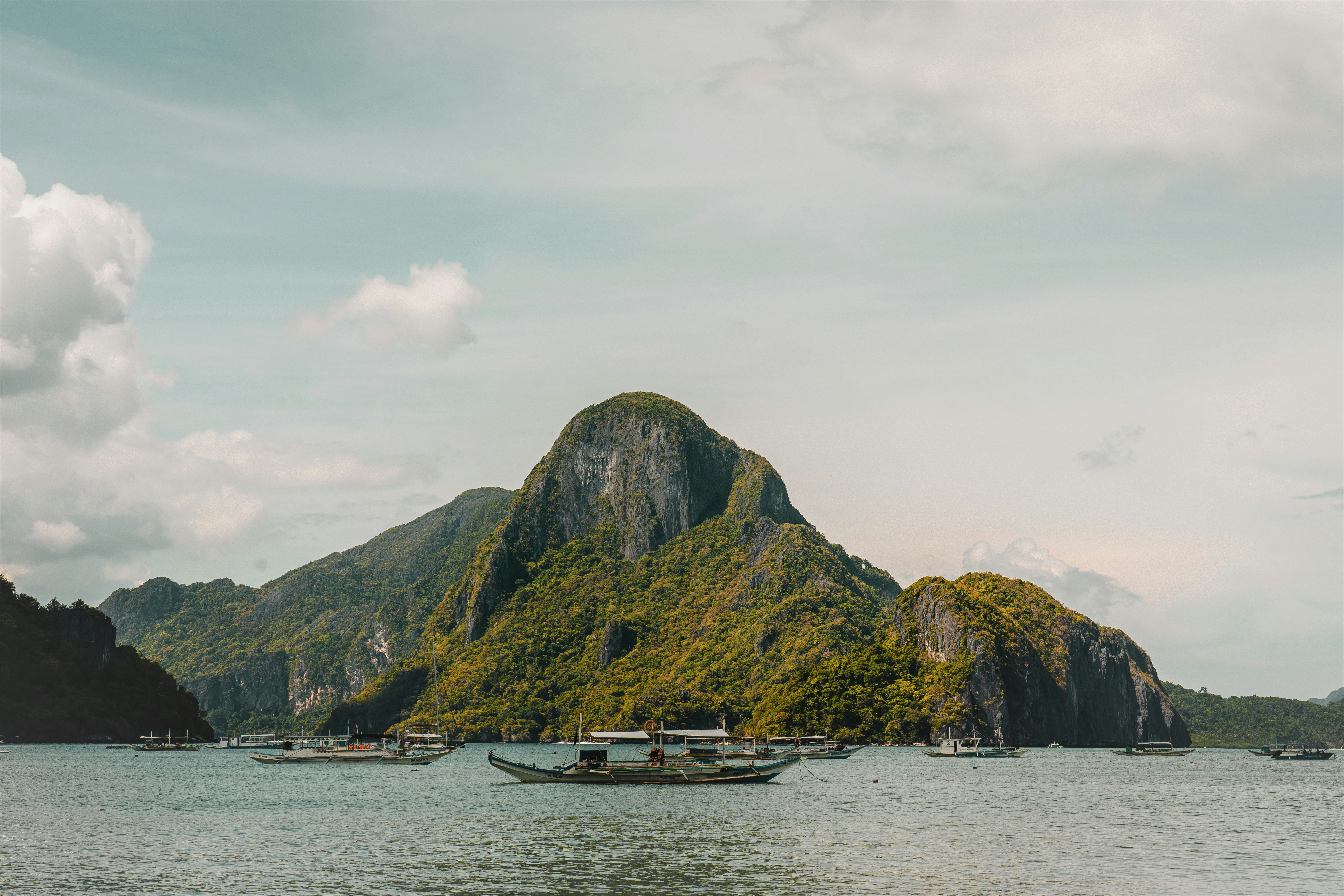 Boats float near a lush, mountainous island.