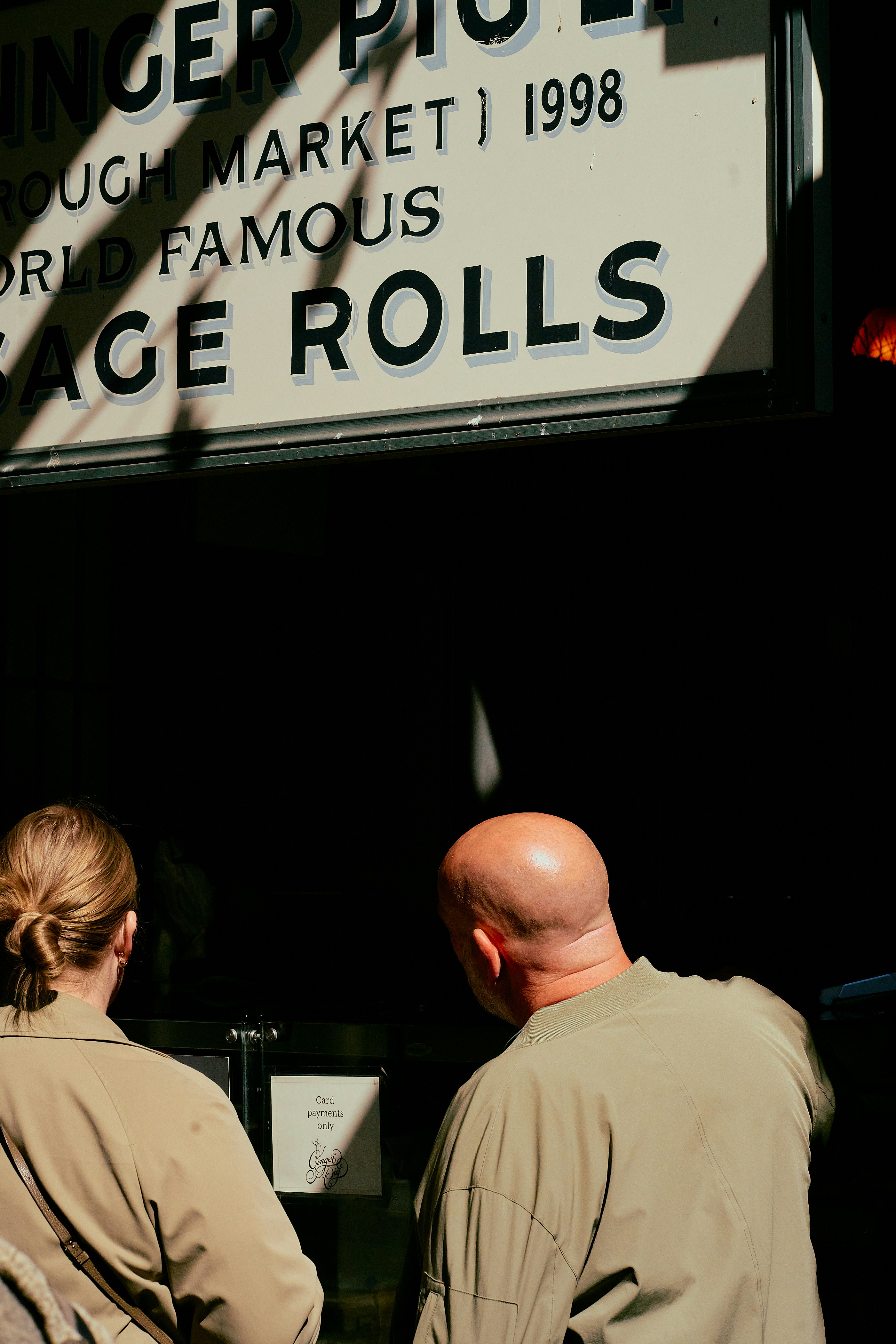 People queue to order sausage rolls at a market.