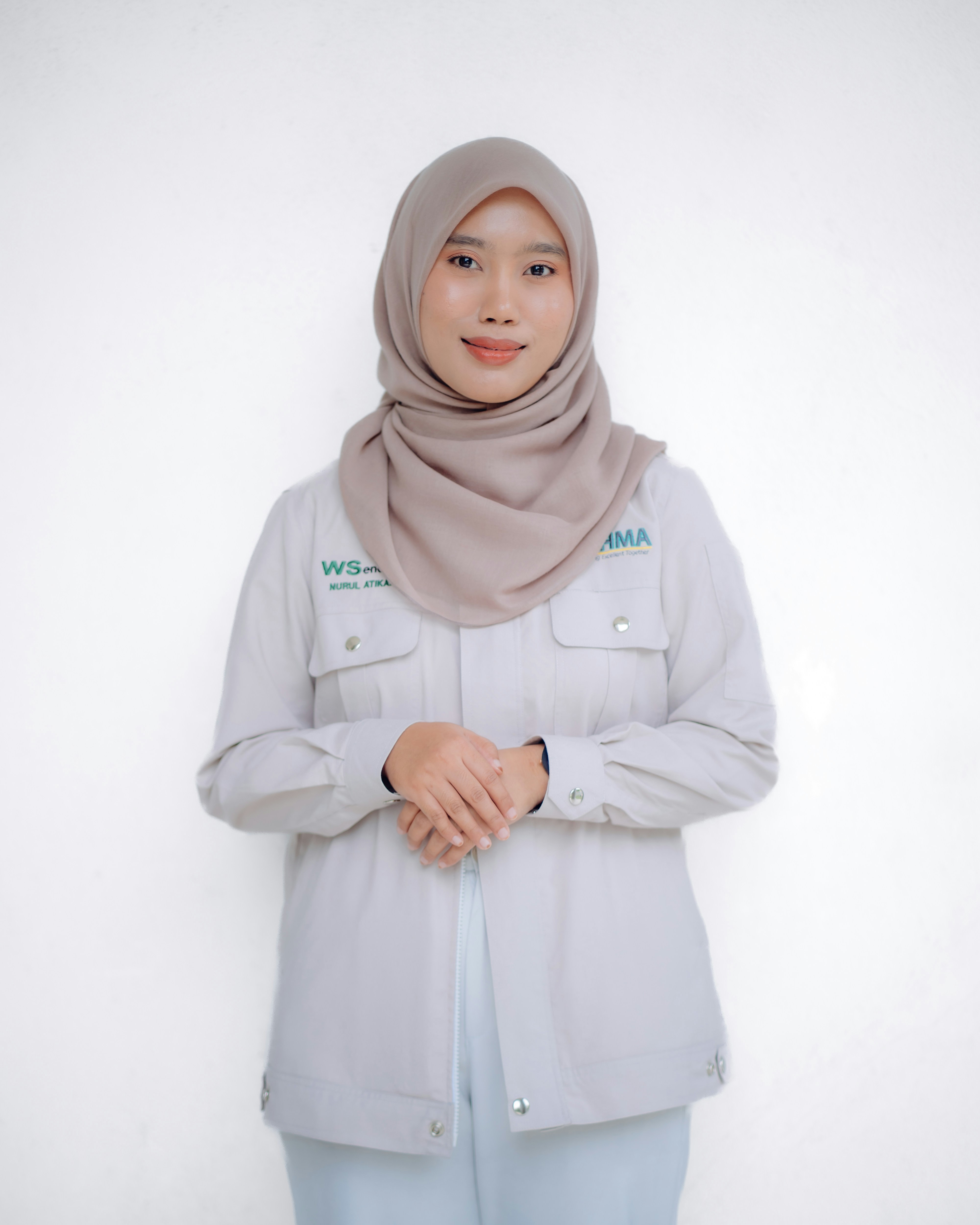 A woman wearing a hijab smiles at the camera.