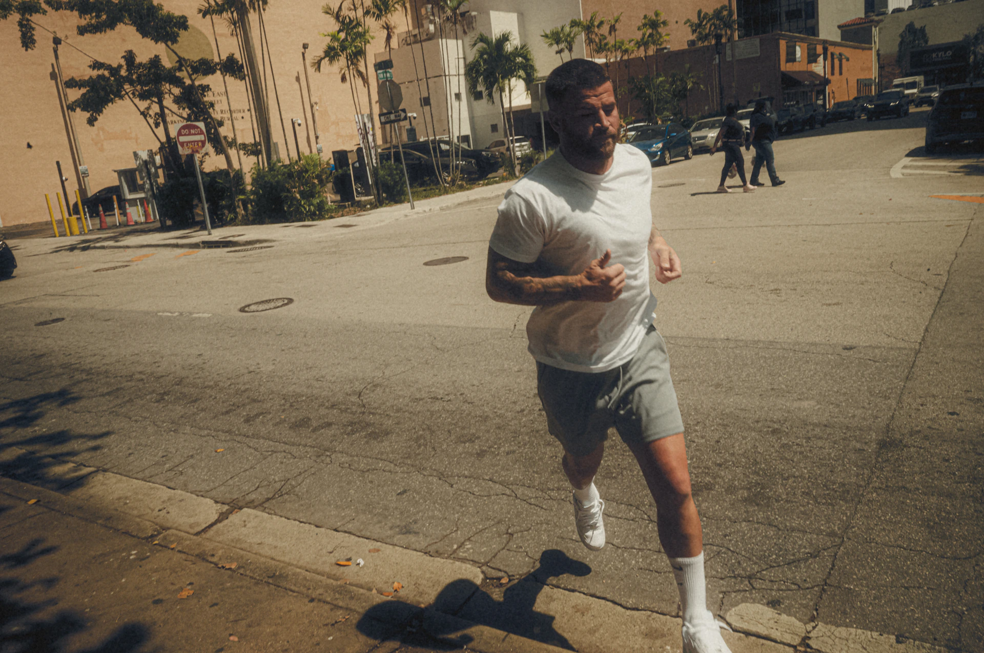 Man is jogging down a sunny city street.