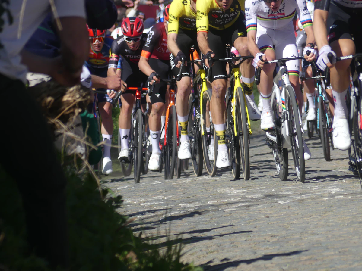 Cyclists race on a cobblestone road under bright sun