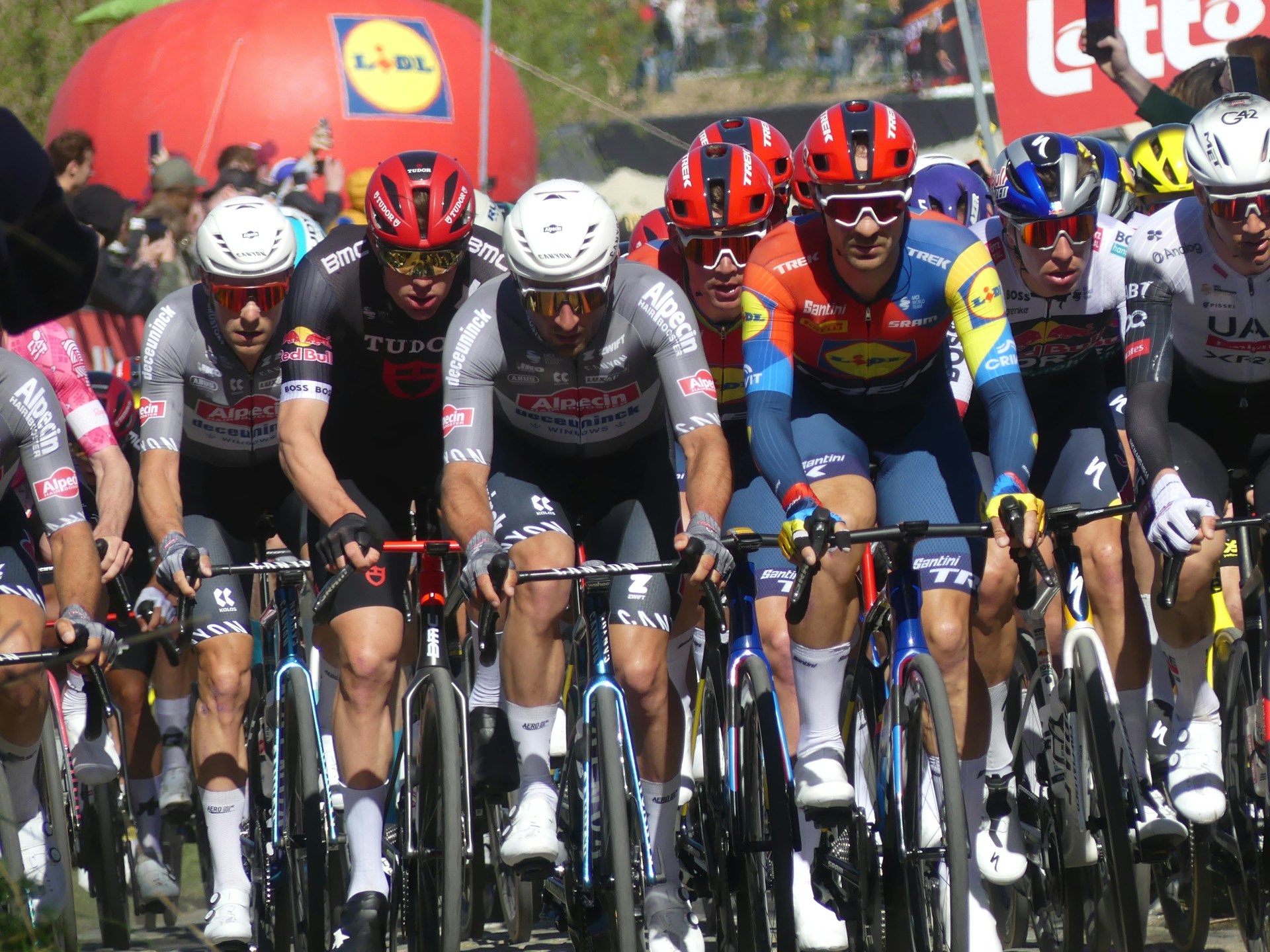 Cyclists in a race, wearing colorful jerseys and branded jerseys.