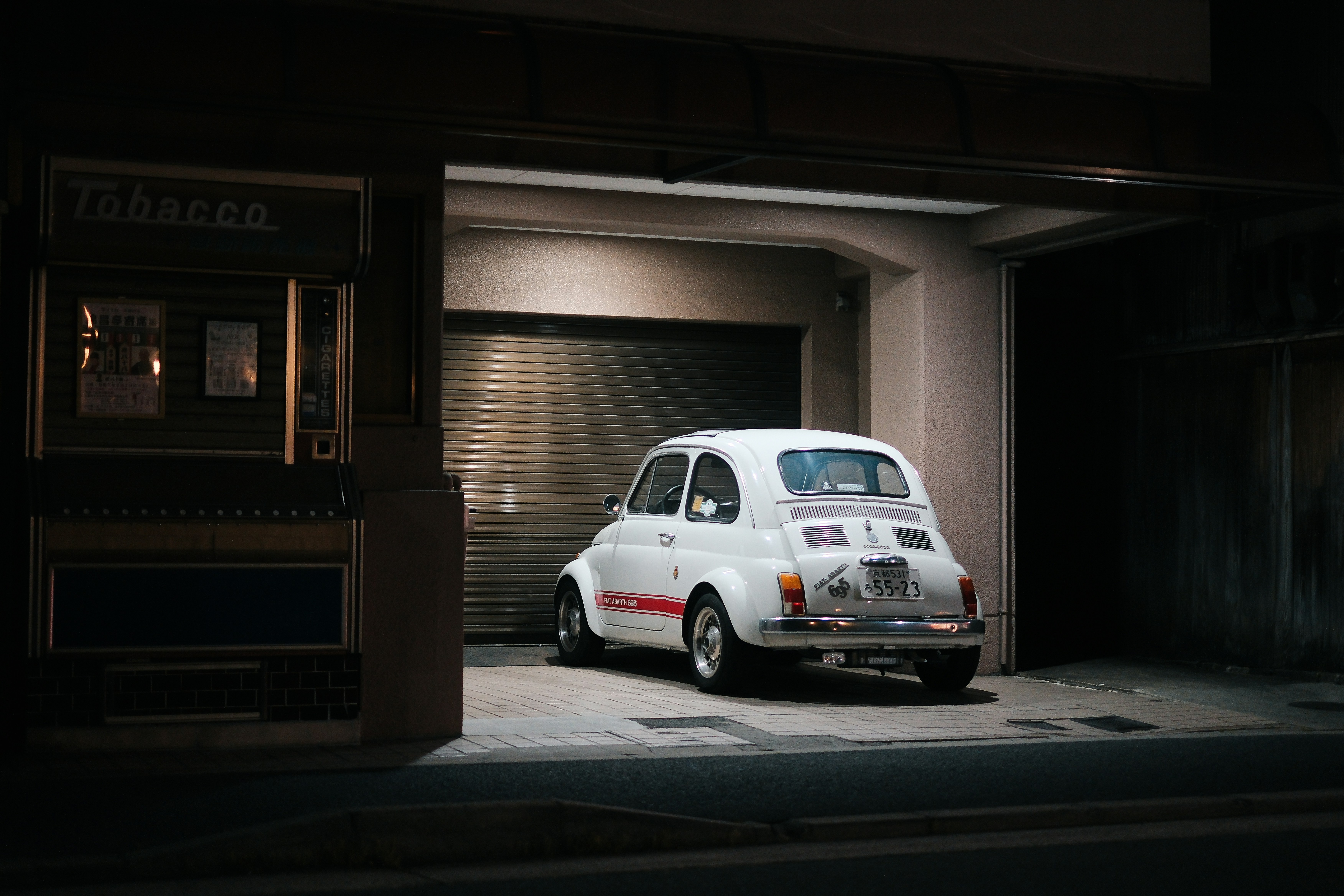 Ein klassisches weißes Auto parkt in einer Garage.