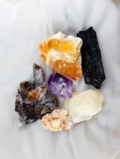 Crystals of various colors rest on white fabric.