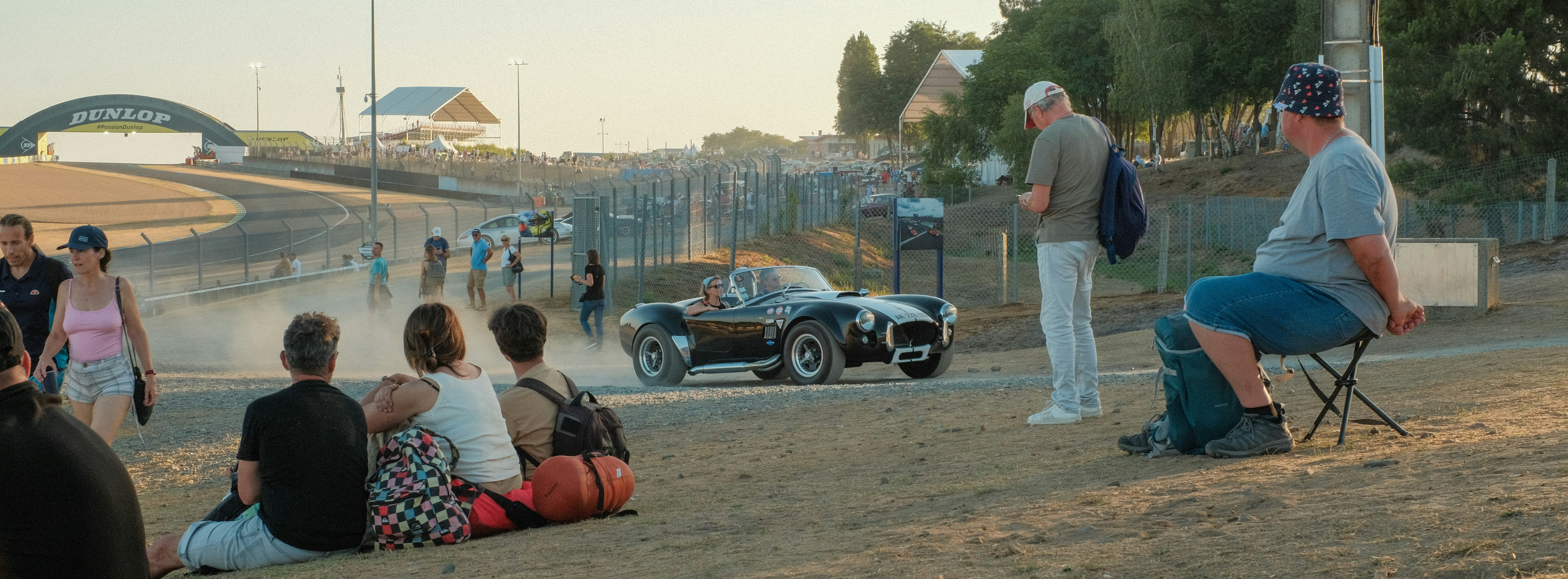 A car drives on a dirt track before spectators.