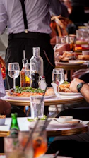 Diners enjoying a meal with a waiter in the background.