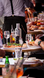 Diners enjoying a meal with a waiter in the background.