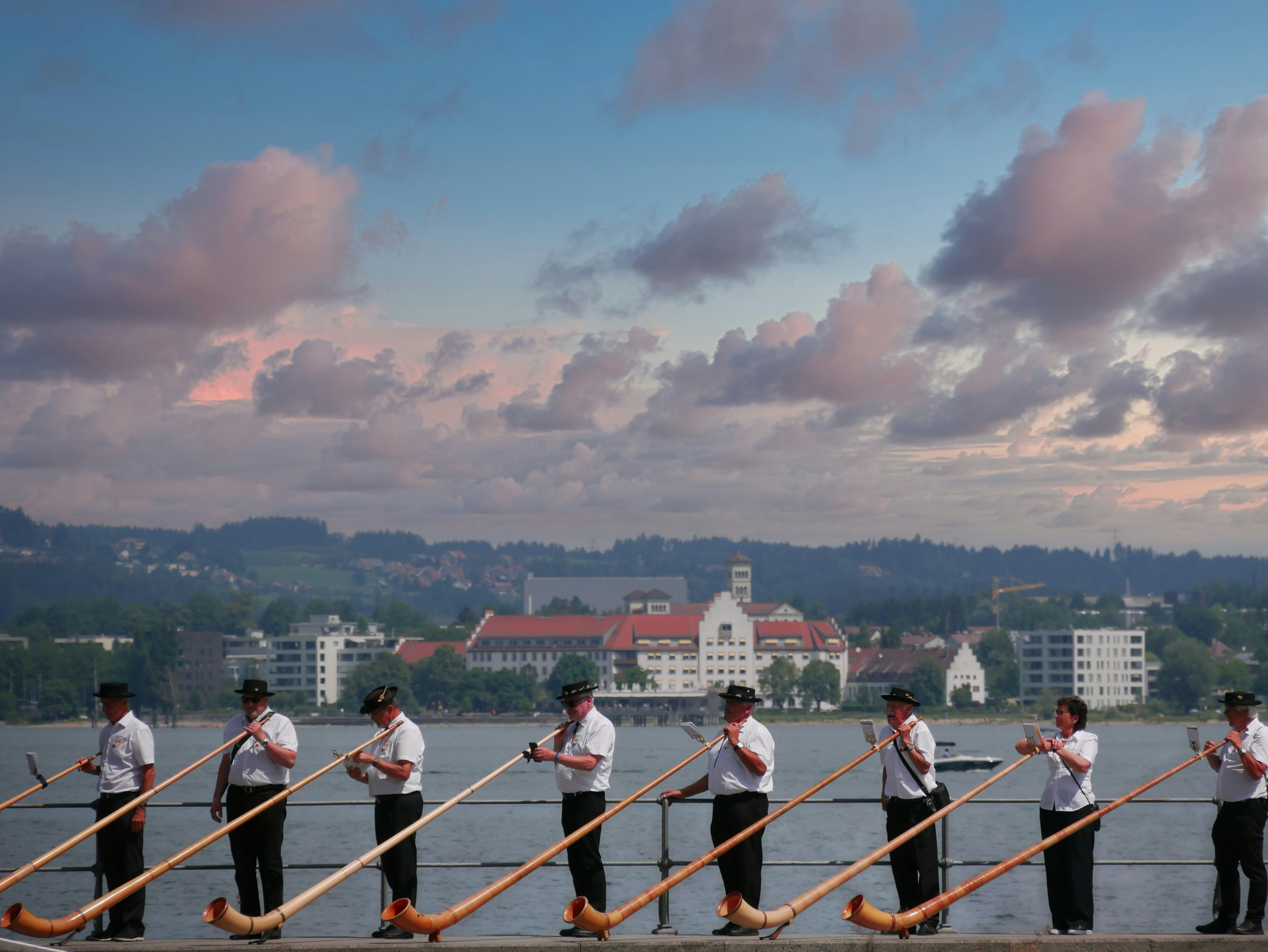 Musicians play alphorns near a beautiful sunset.