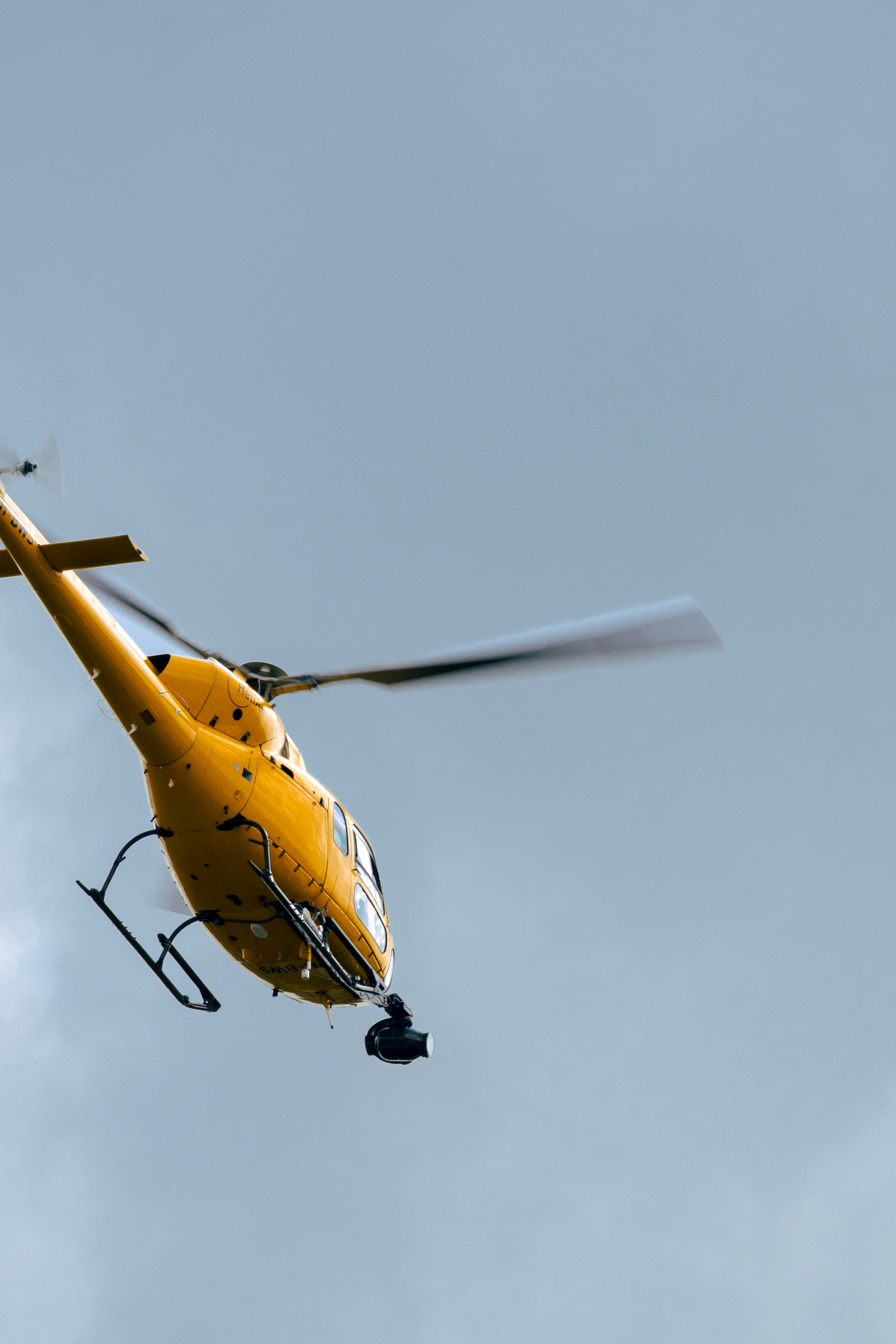 Un hélicoptère jaune vole dans le ciel.