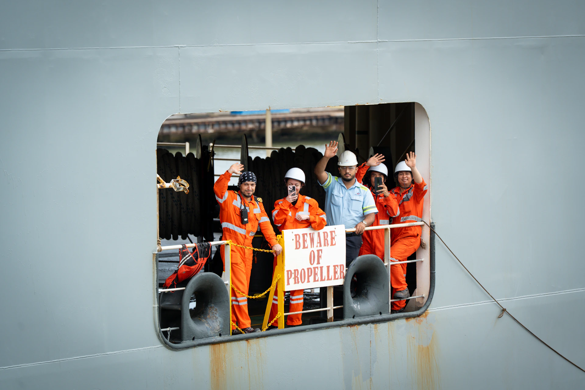 Crew members wave from a ship's opening