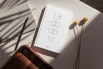 A white notebook and dried flowers on a table.