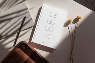 A white notebook and dried flowers on a table.