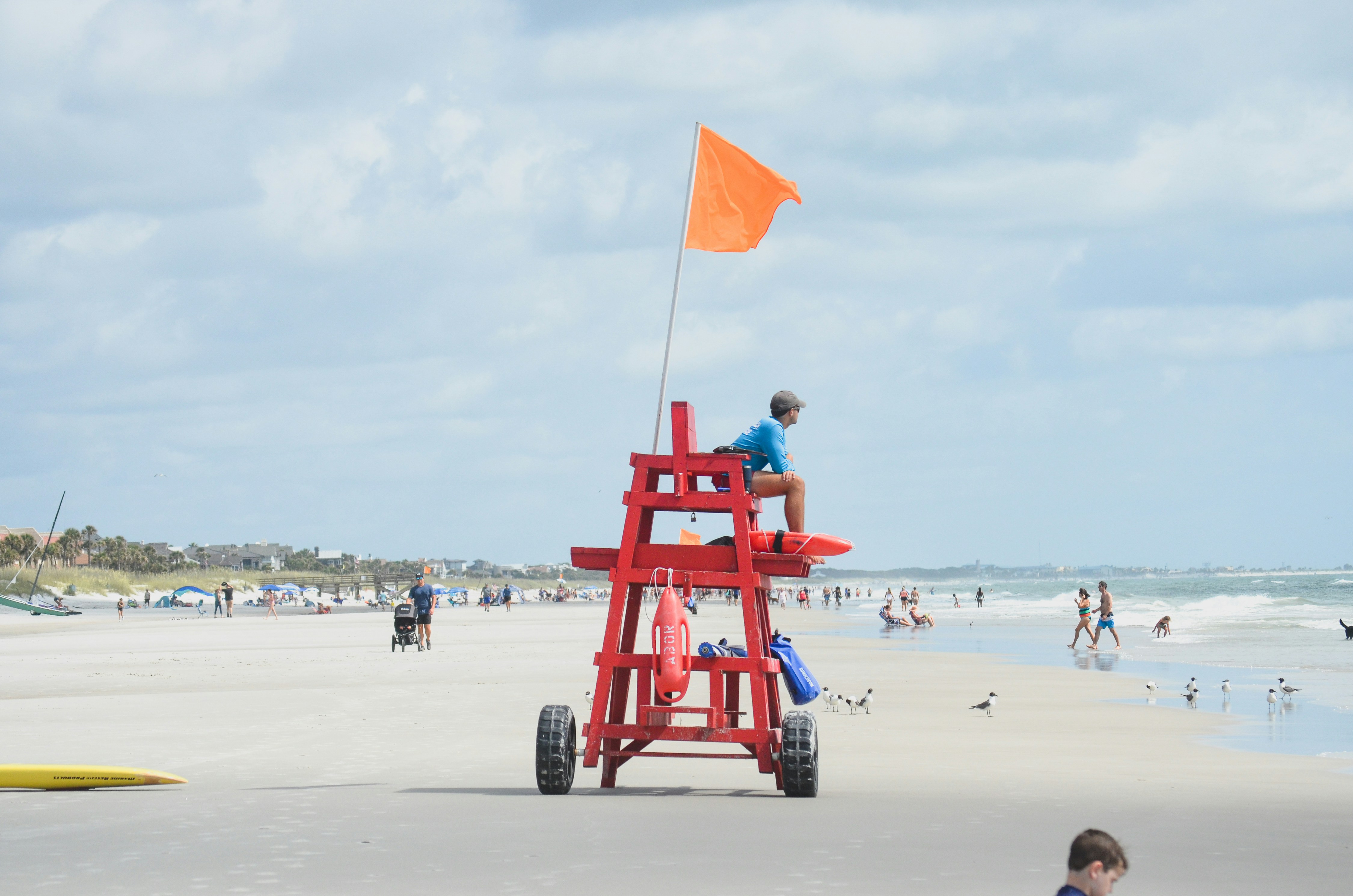 A lifeguard watches the beach with an orange flag.