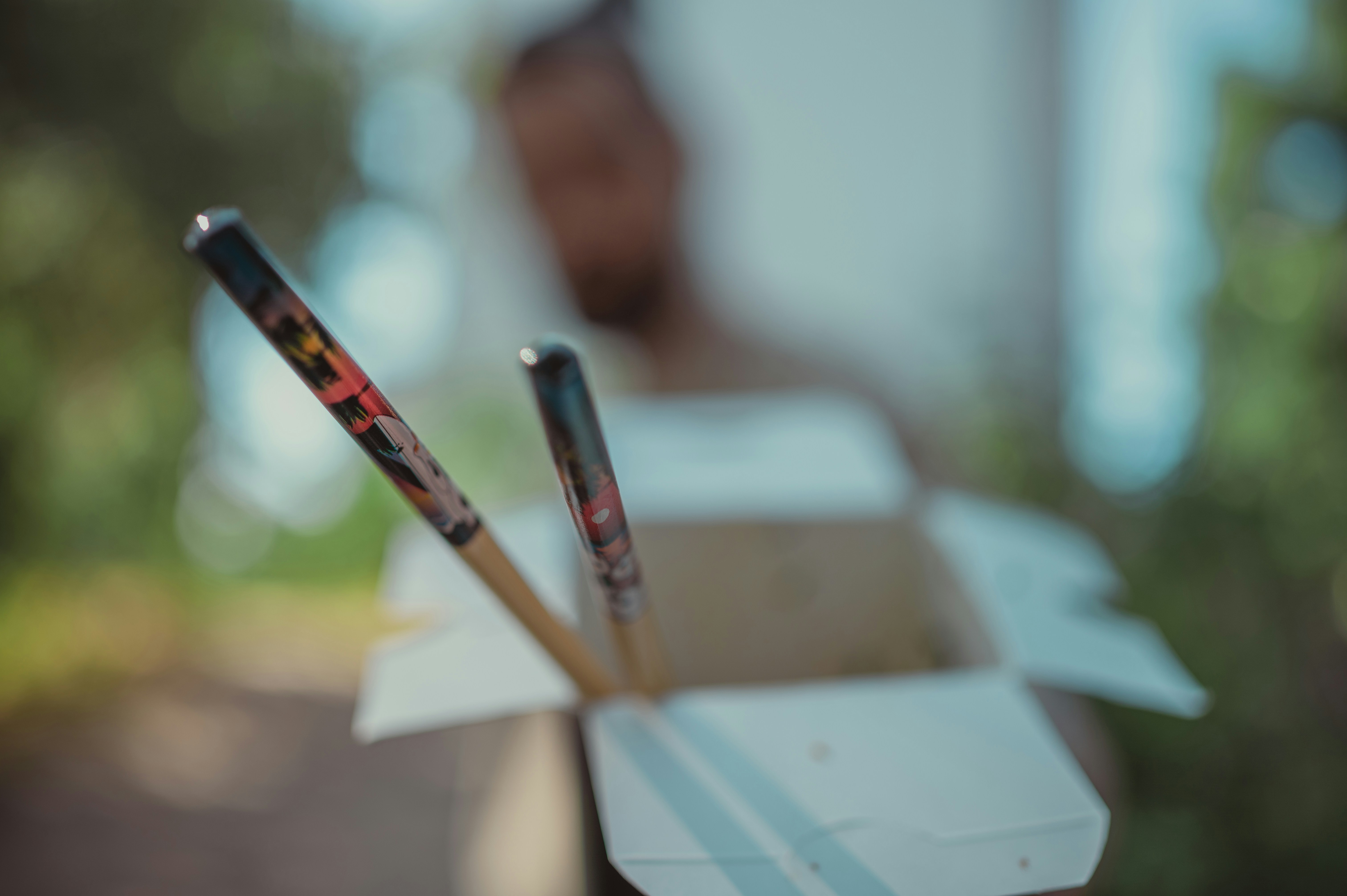 Chopsticks and food takeout container in hand.
