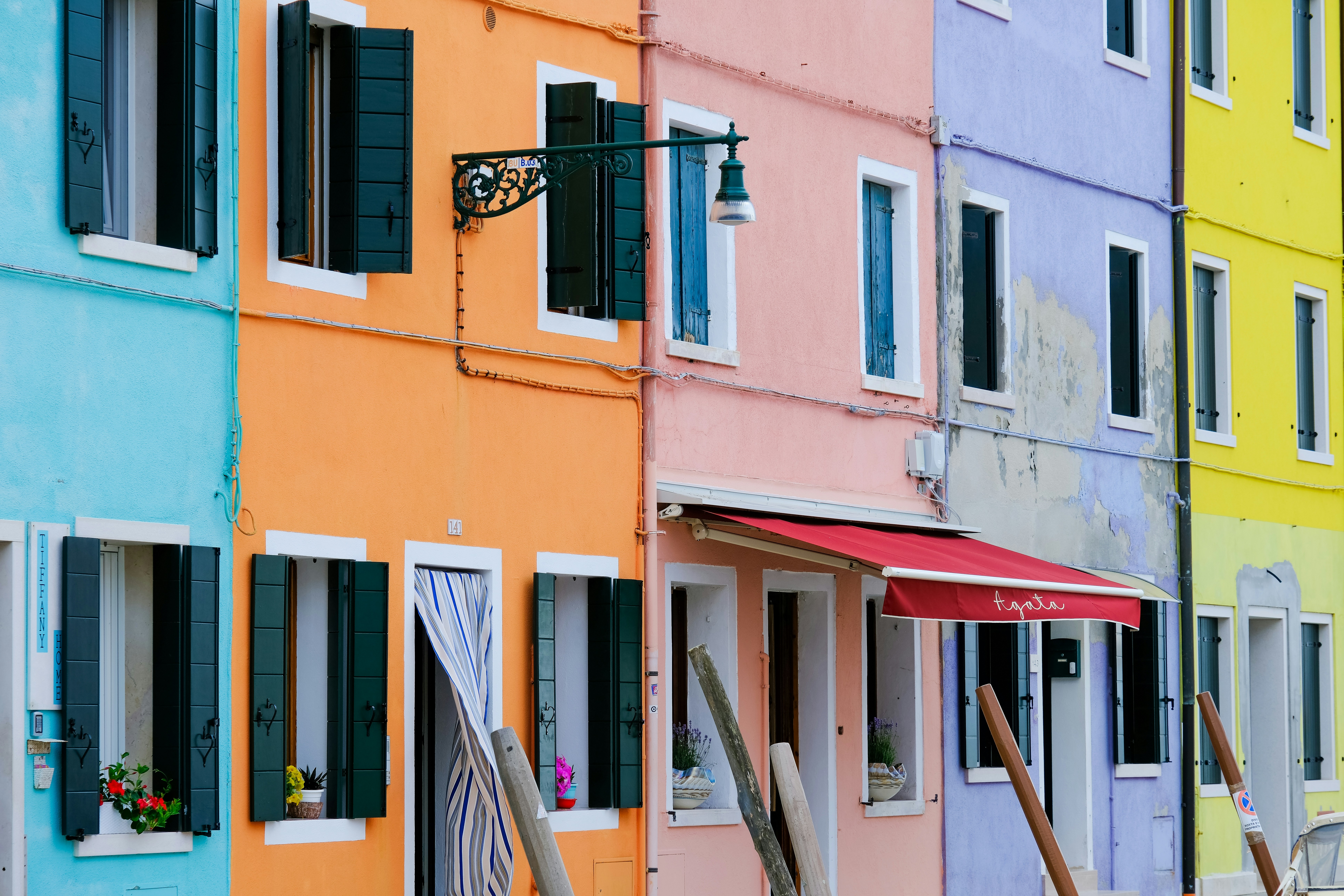 Colorful buildings line a street with shutters.