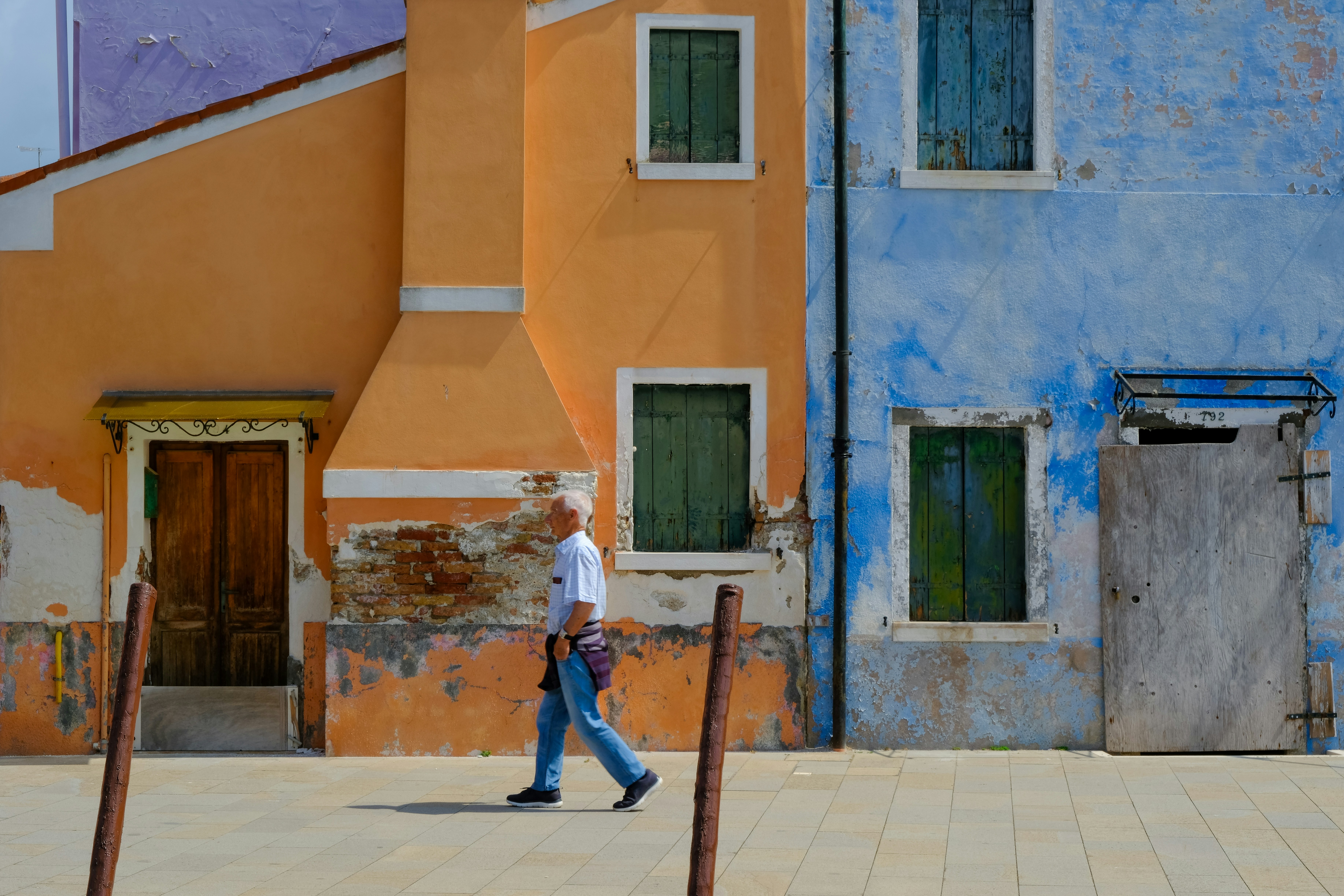 Man walks past colorful buildings in burano.