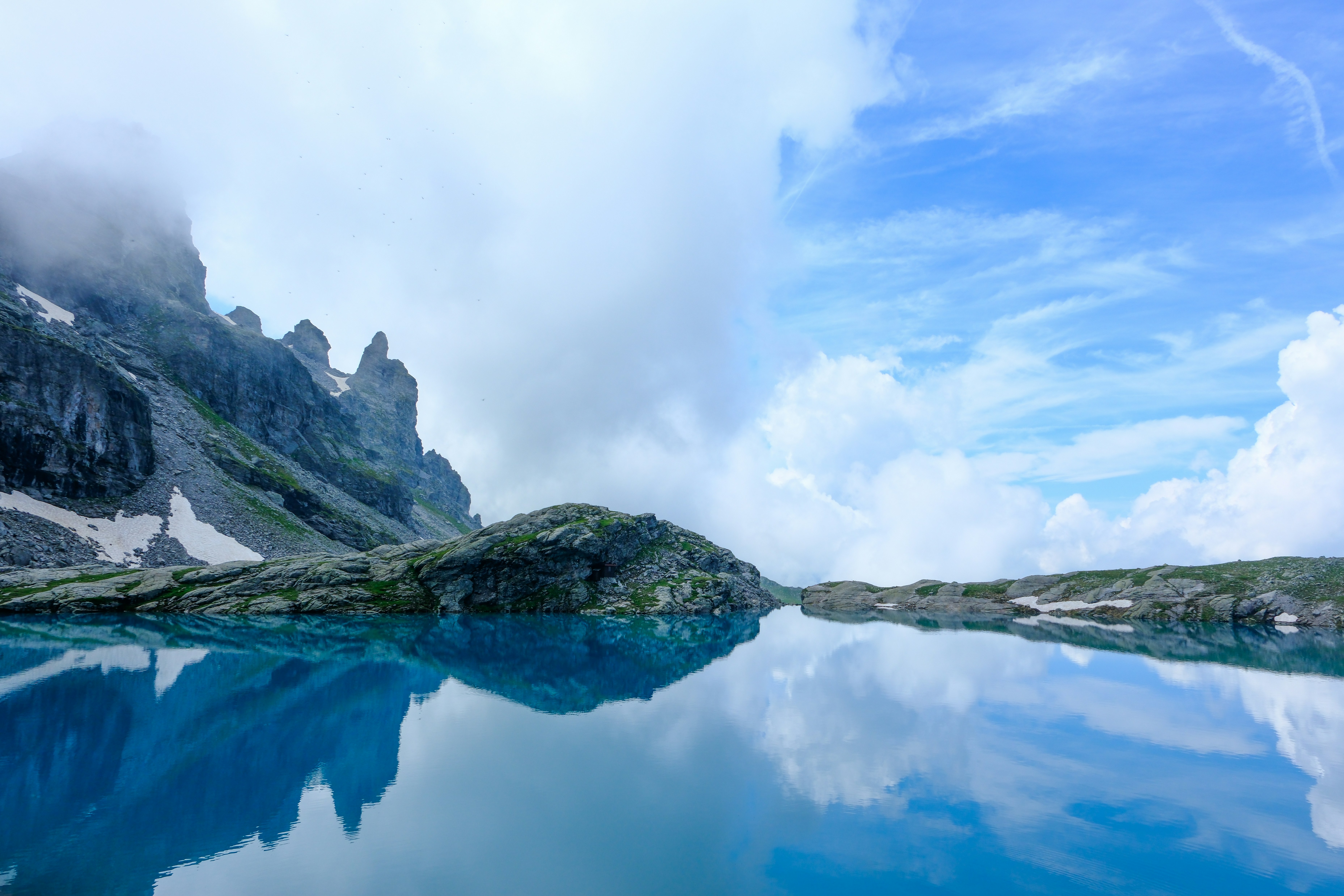 Mountains and a lake reflect a bright sky.