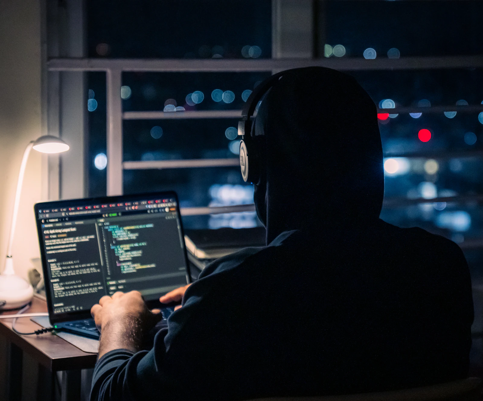 A person coding on a laptop at night