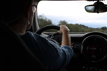 A woman drives a car down the road.