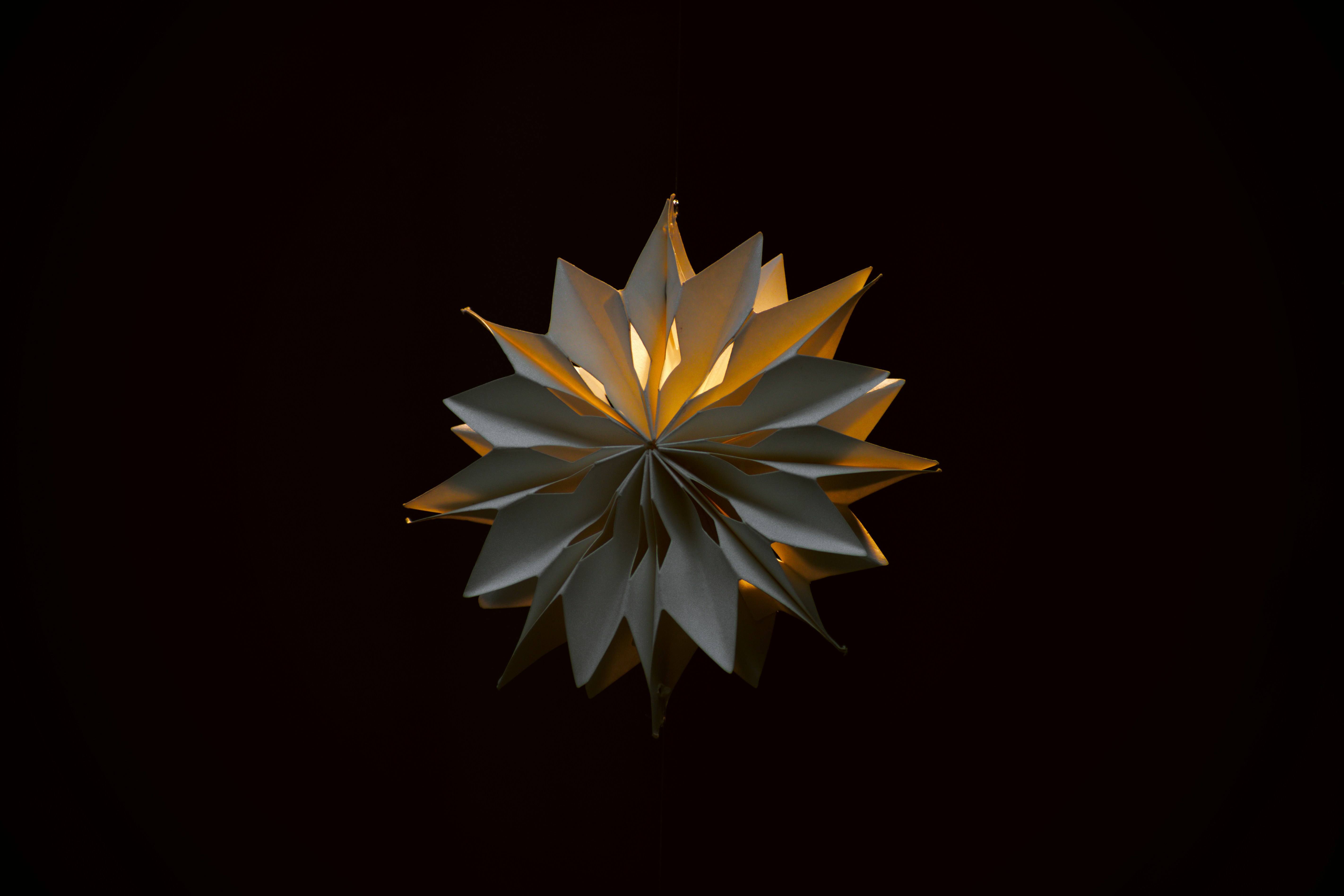 A paper star shines brightly against darkness.