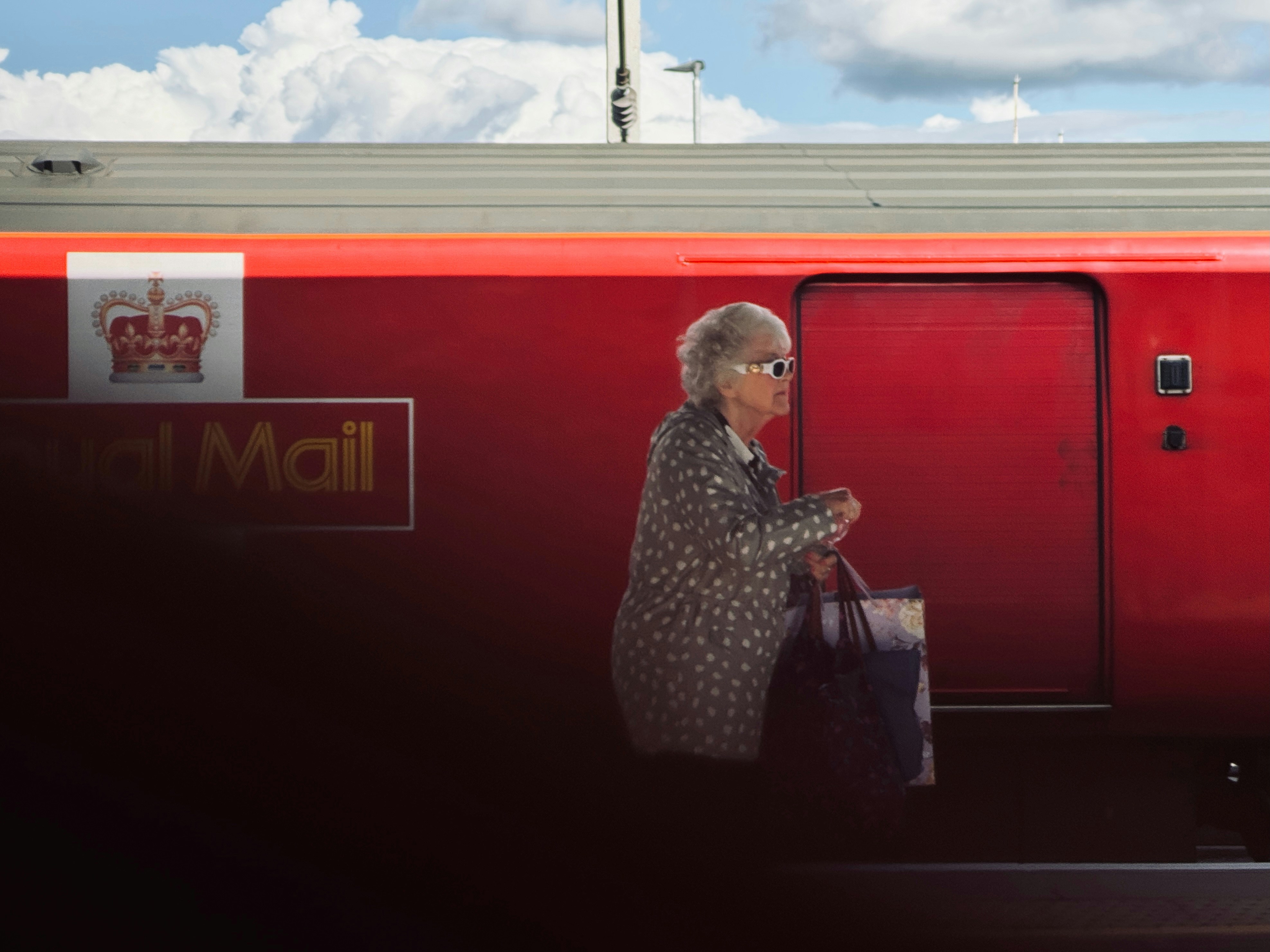 Woman exits royal mail train with a shopping bag.