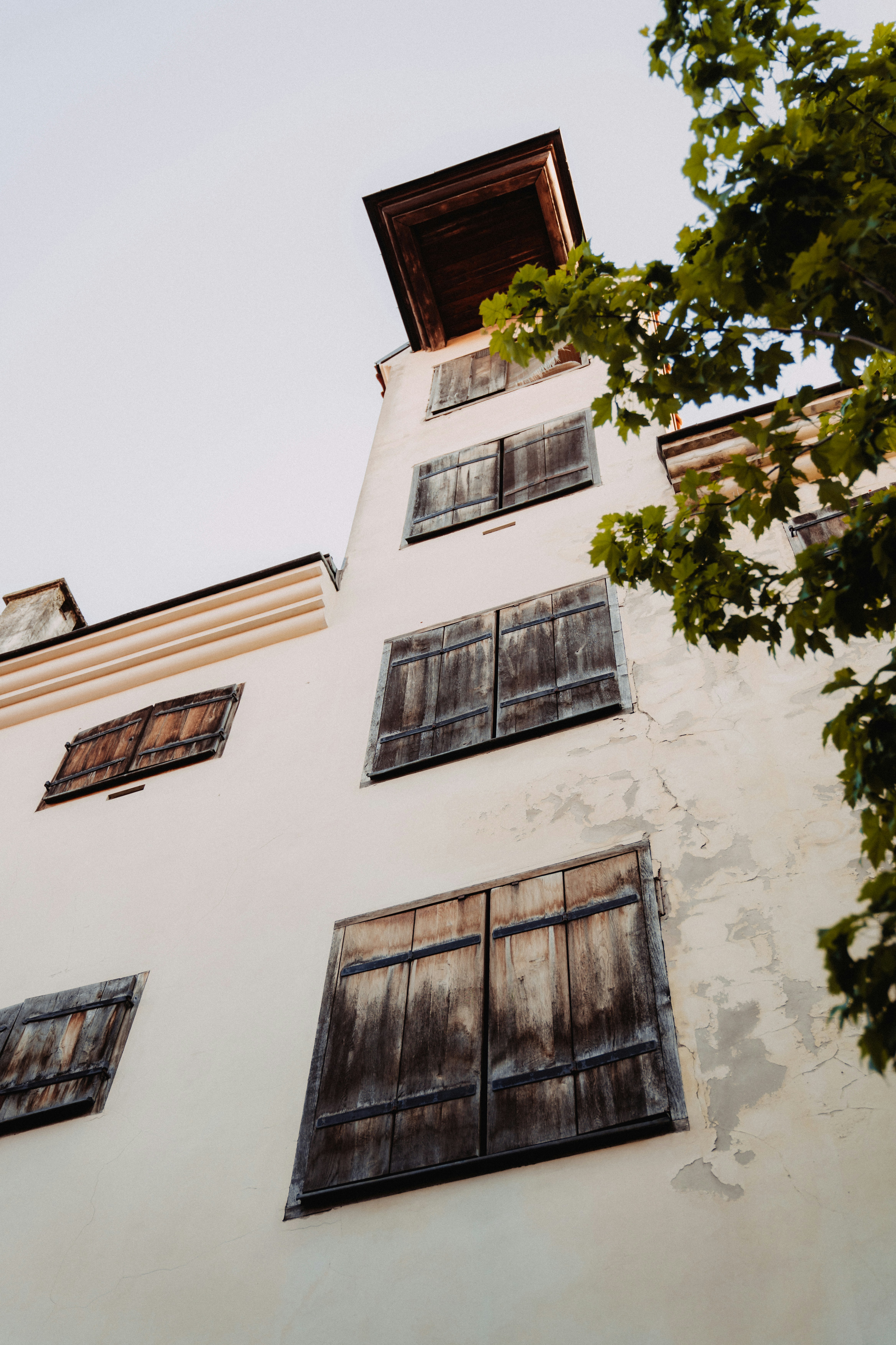 風化した木製のシャッターが付いた背の高い白い建物。