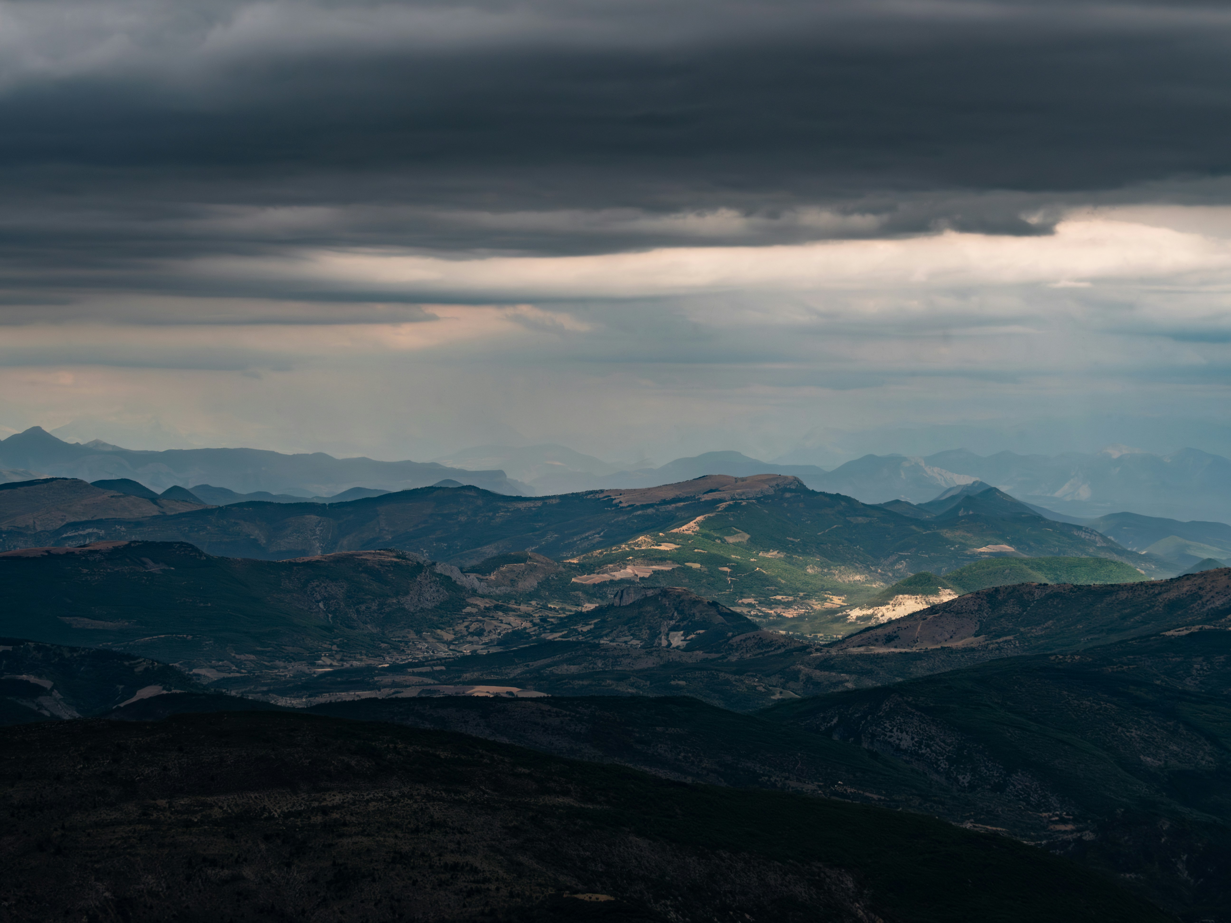 Mountains bask in the sunlight through cloudy skies.
