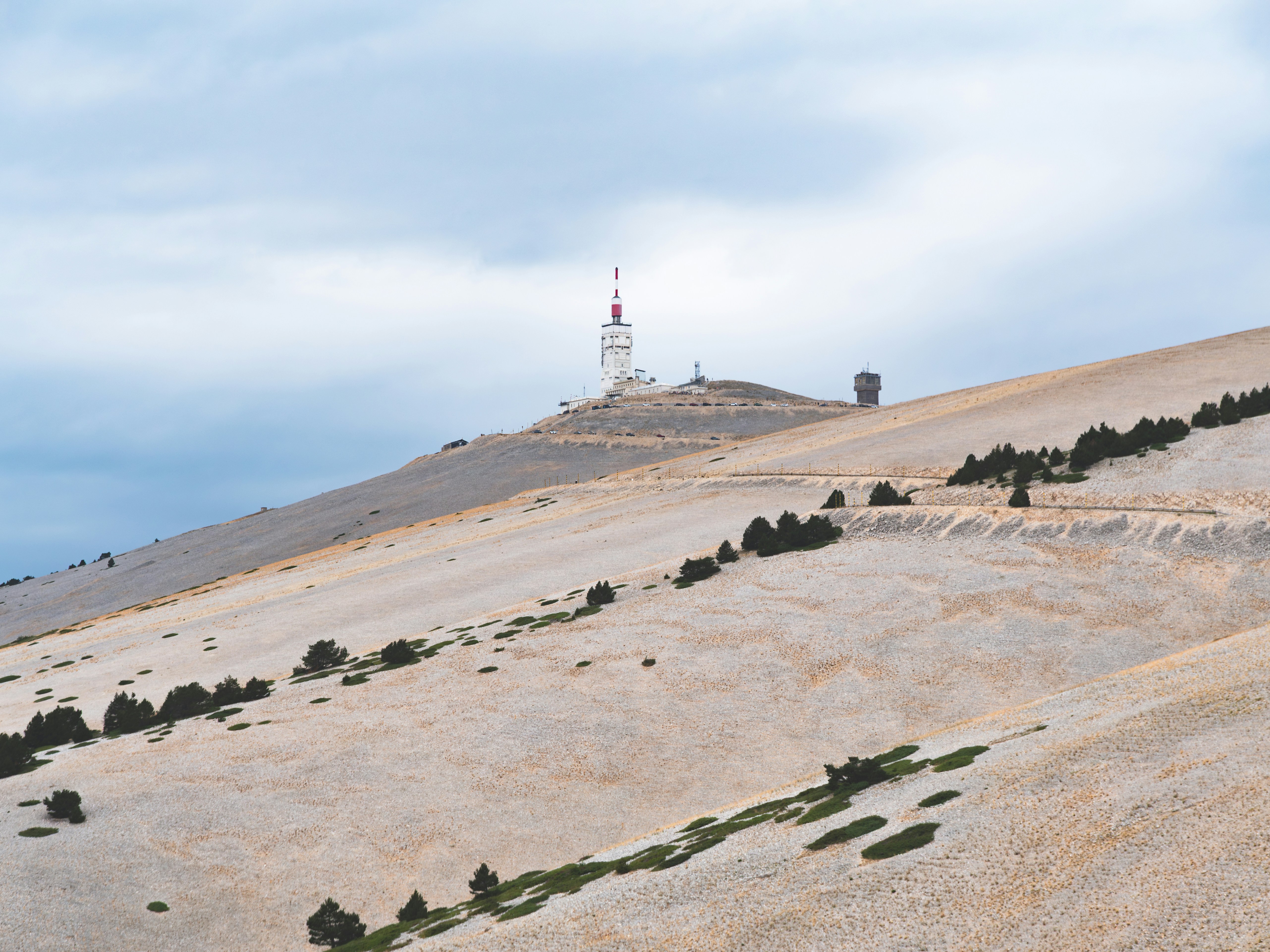 A mountain peak with antenna towers under a cloudy sky.