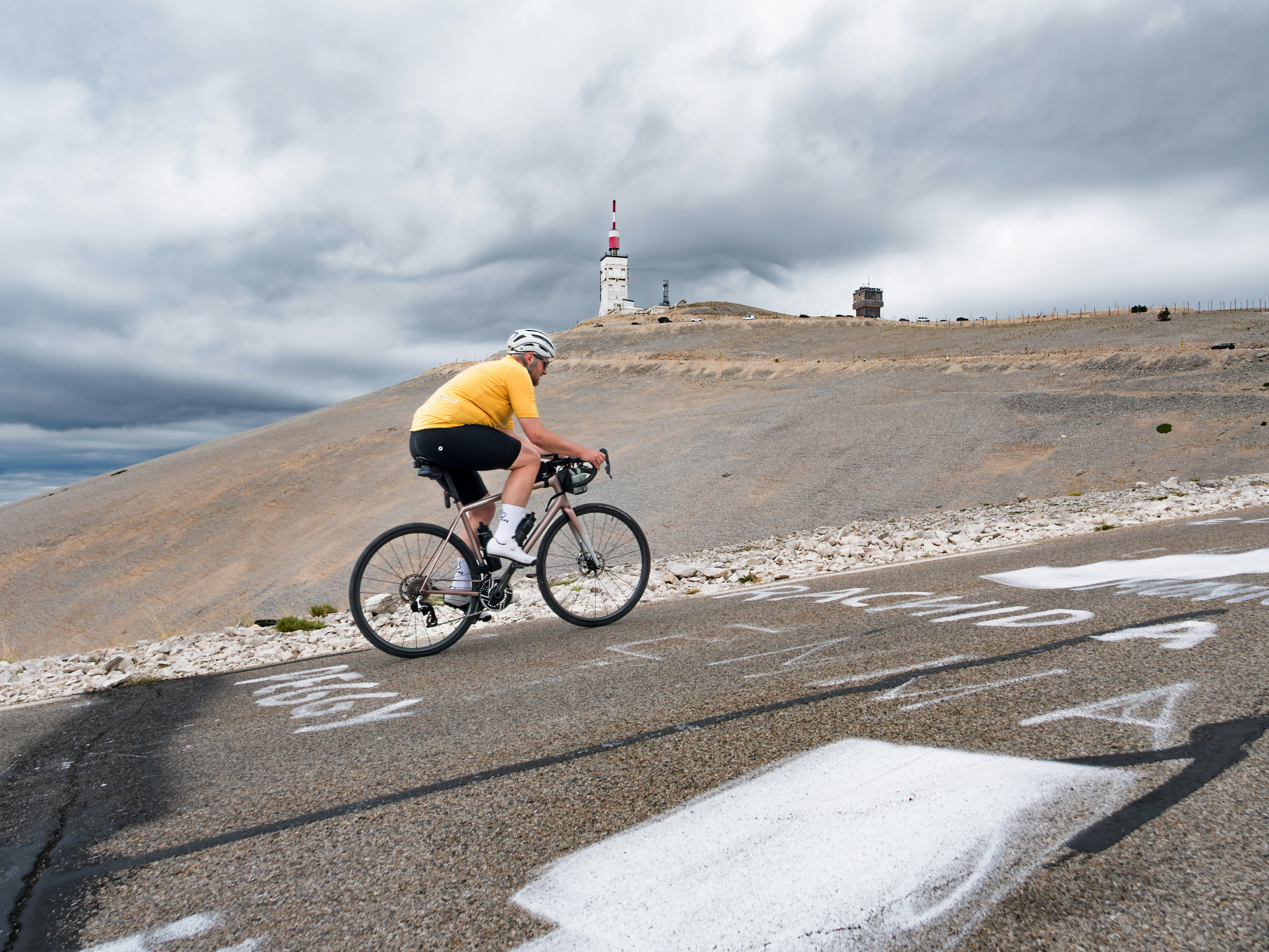 A cyclist rides uphill with a landmark in view.