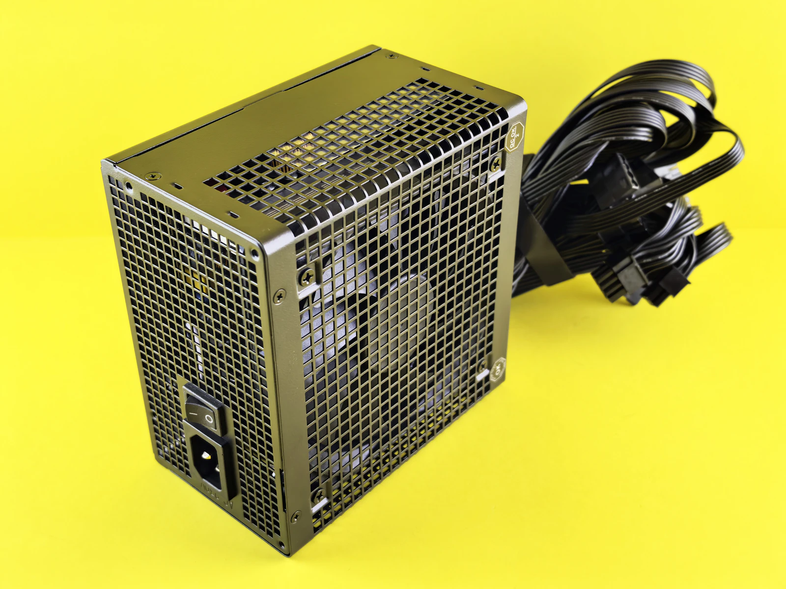 Bloc d'alimentation de PC avec ses câbles sur fond jaune