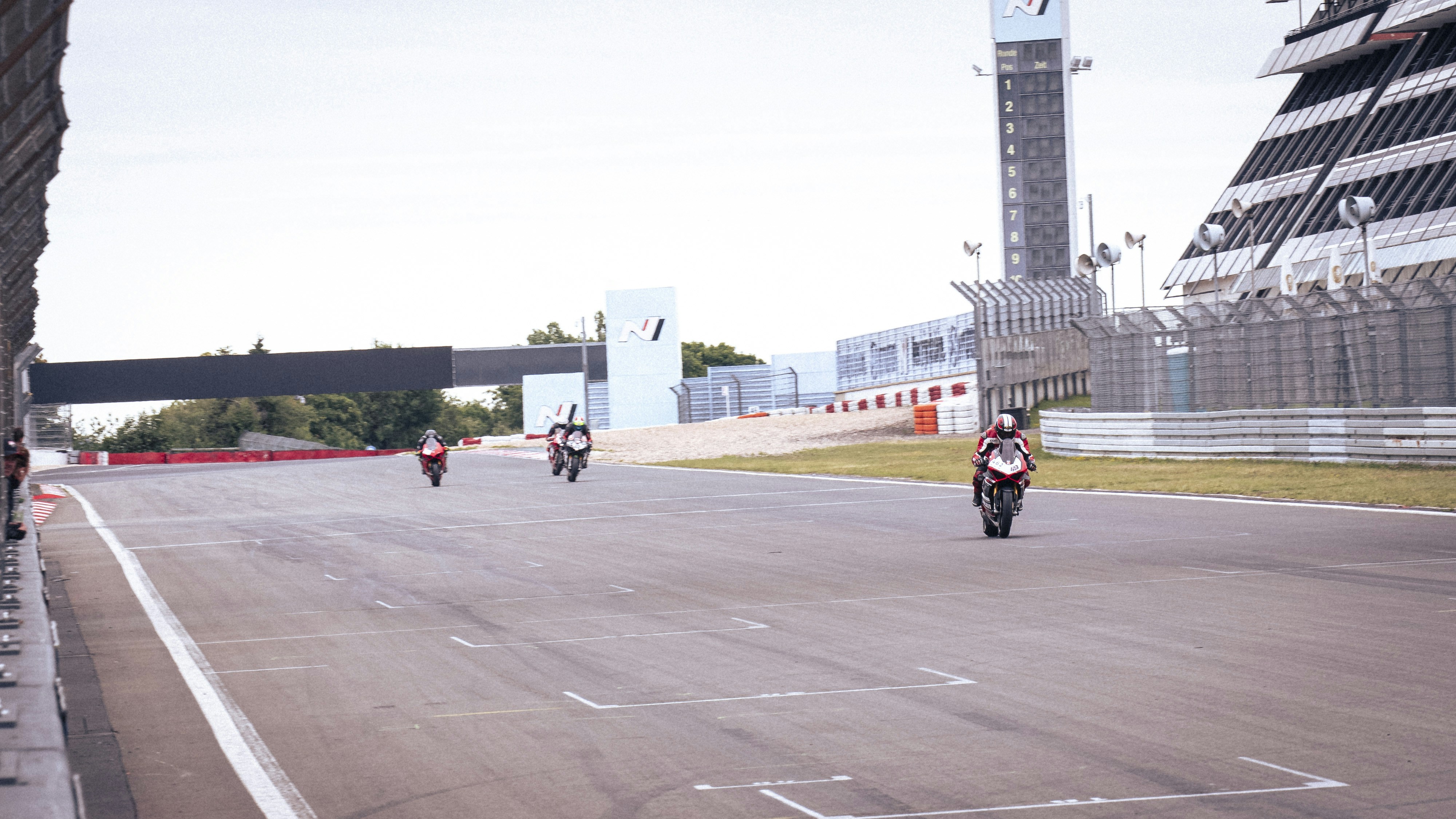 Motorcycles race on the track in the distance.