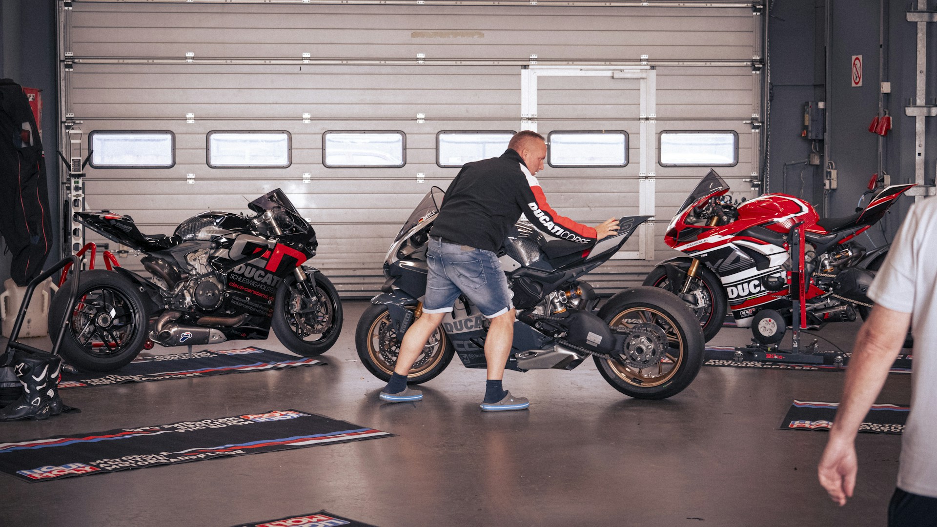 A man cleans a motorcycle in a garage.