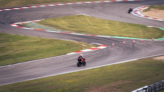 Motorcycles race around a winding racetrack.