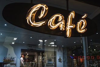 A neon "café" sign glows outside a shop.