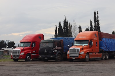 Three trucks are parked in a lot.