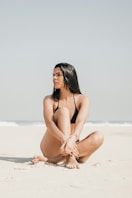 Woman in a bikini sits on the beach.