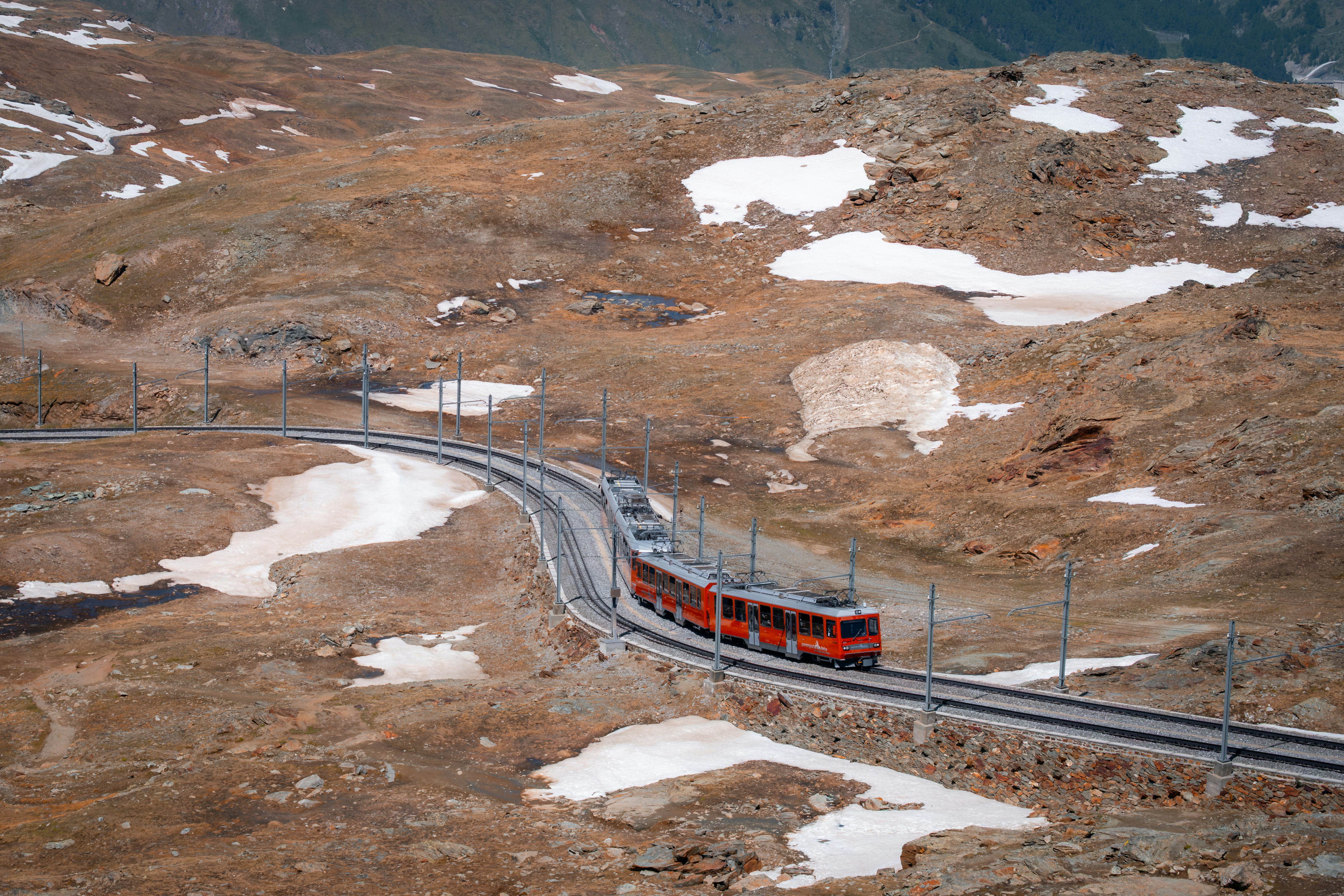 Un train rouge circule le long d’une voie sinueuse.