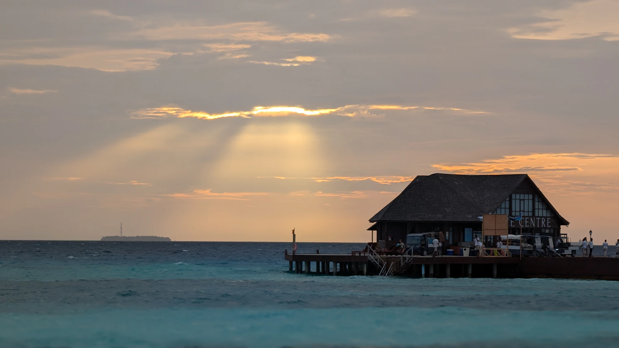 Low sunlight over water and a thatched structure at a Maldives resort