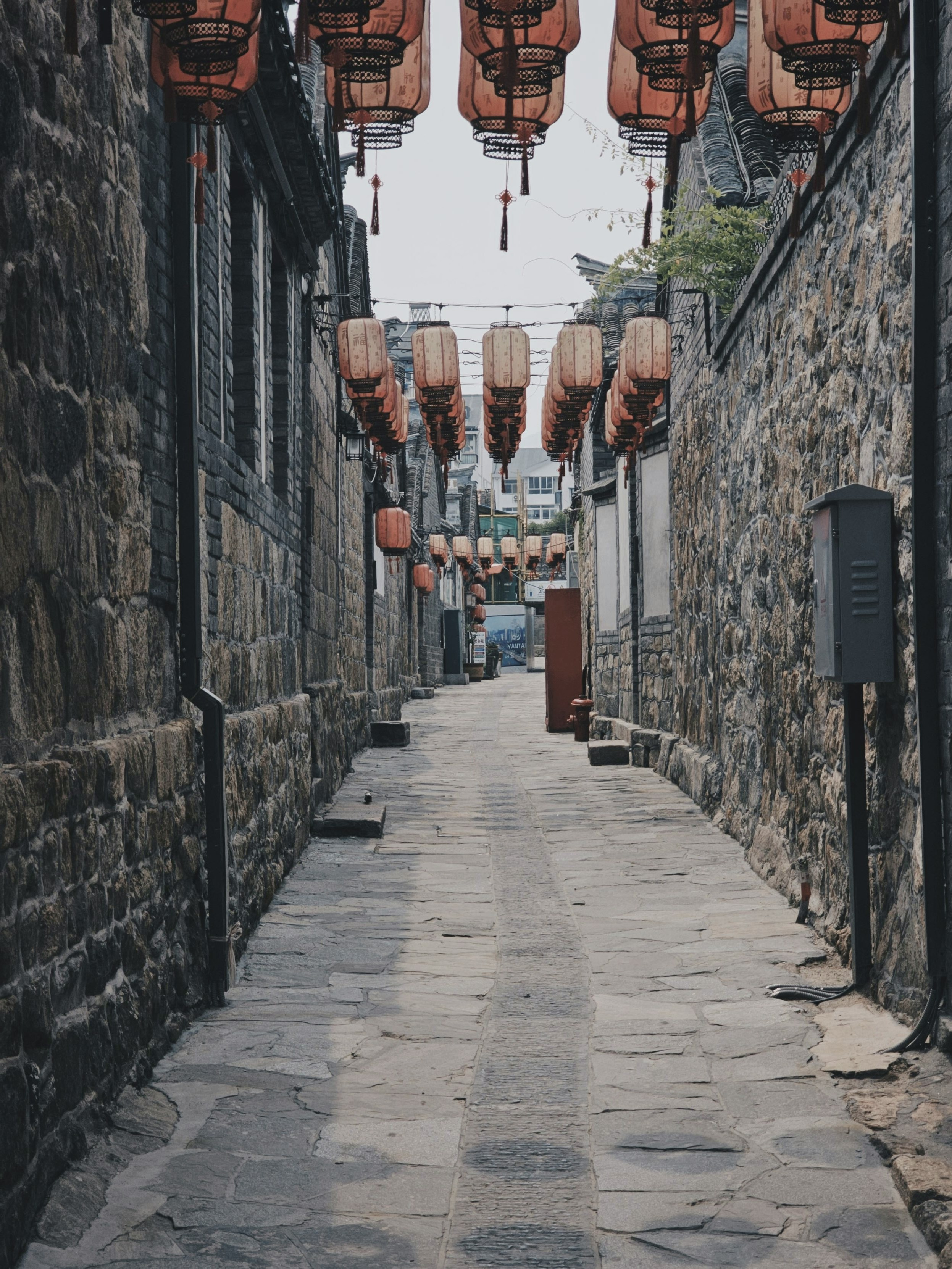 Lanterns hang above a cobblestone alley.