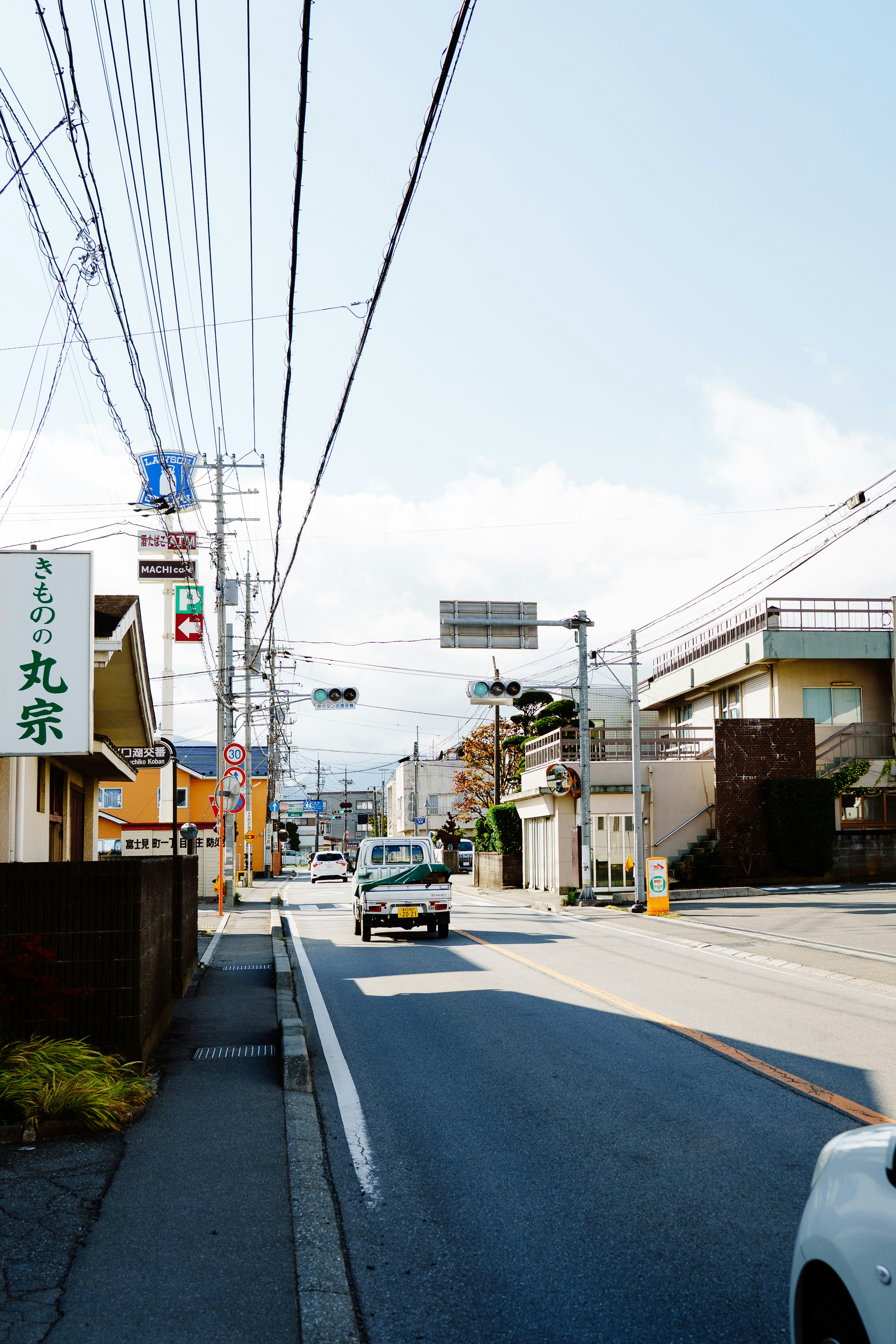 A car drives down a sunny street.