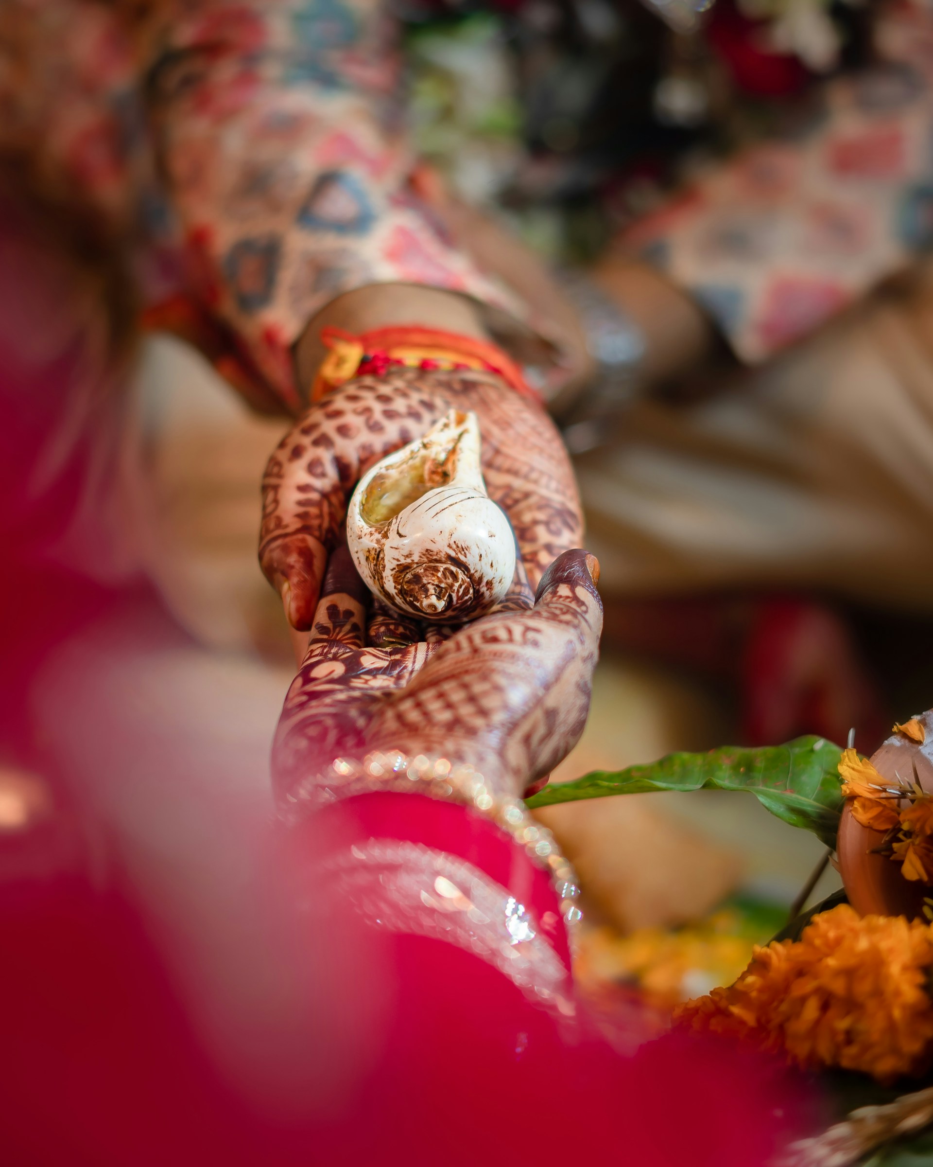 A decorated hand holds a sacred conch shell.