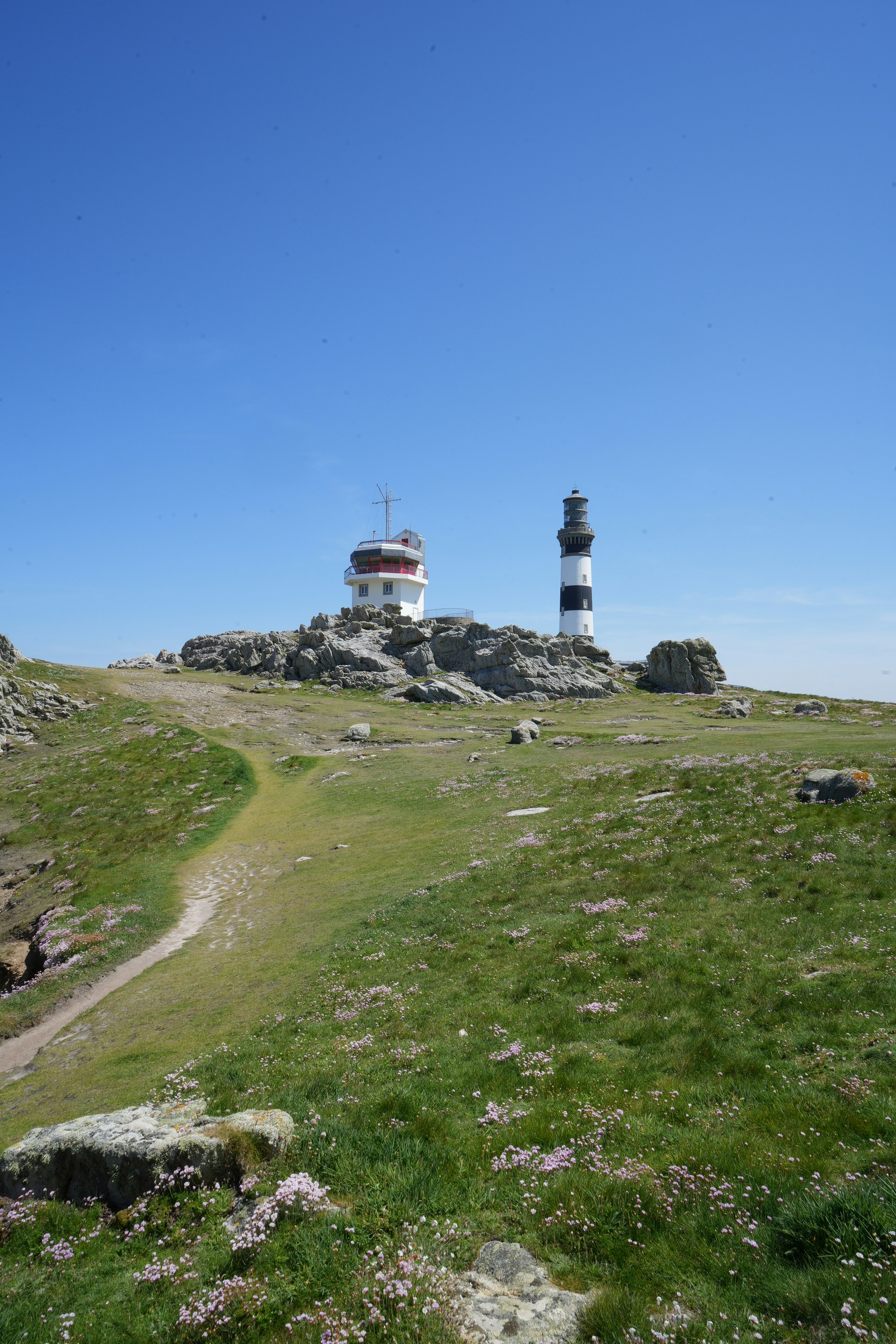 Deux phares se trouvent au sommet d’une colline rocheuse.