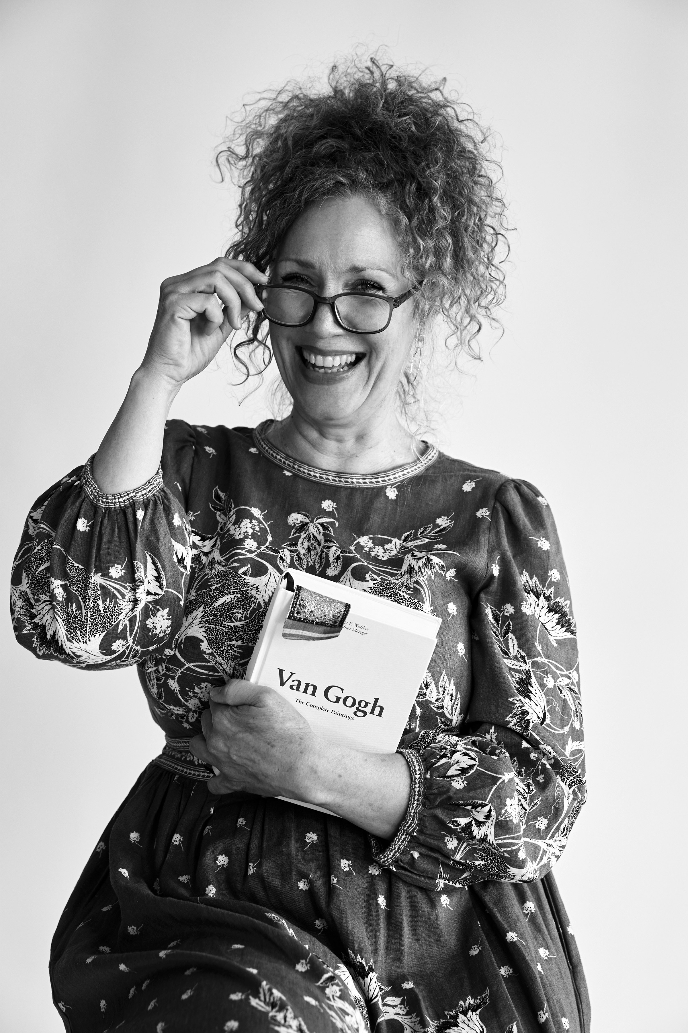 Mujer sonriendo, sosteniendo un libro sobre Van Gogh.