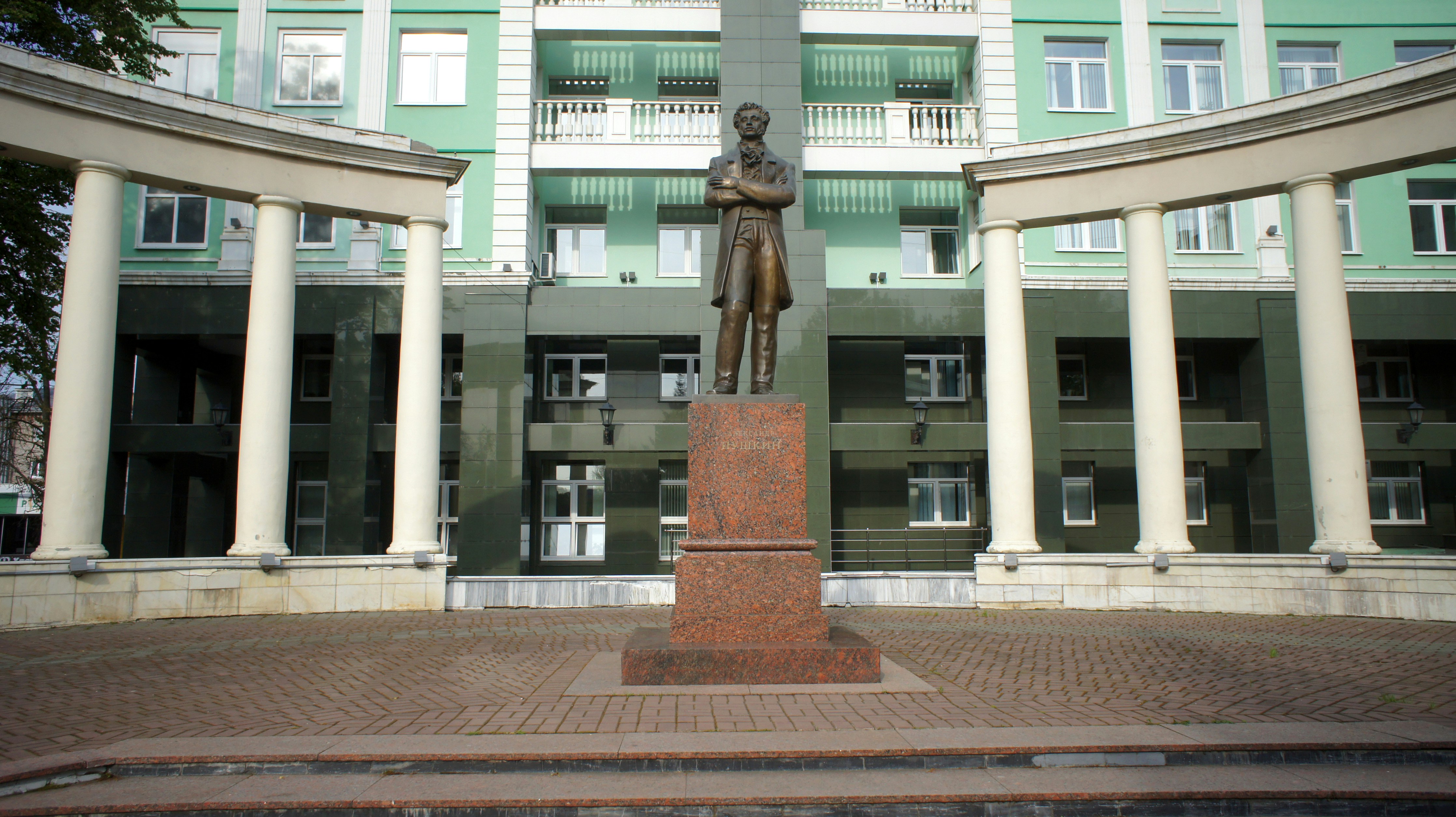 A statue stands in front of a green building.