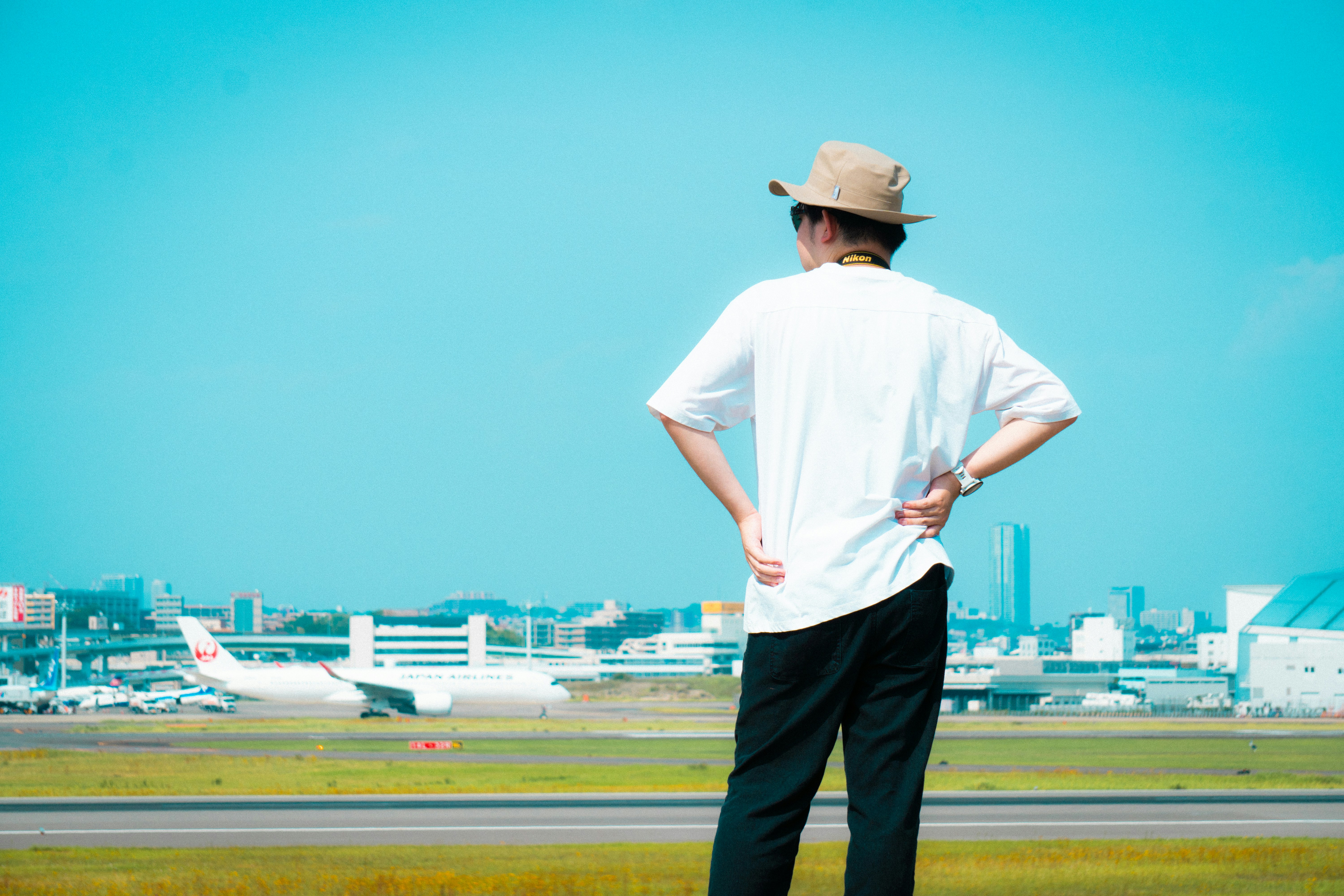 Man in hat at airport looks towards sky.