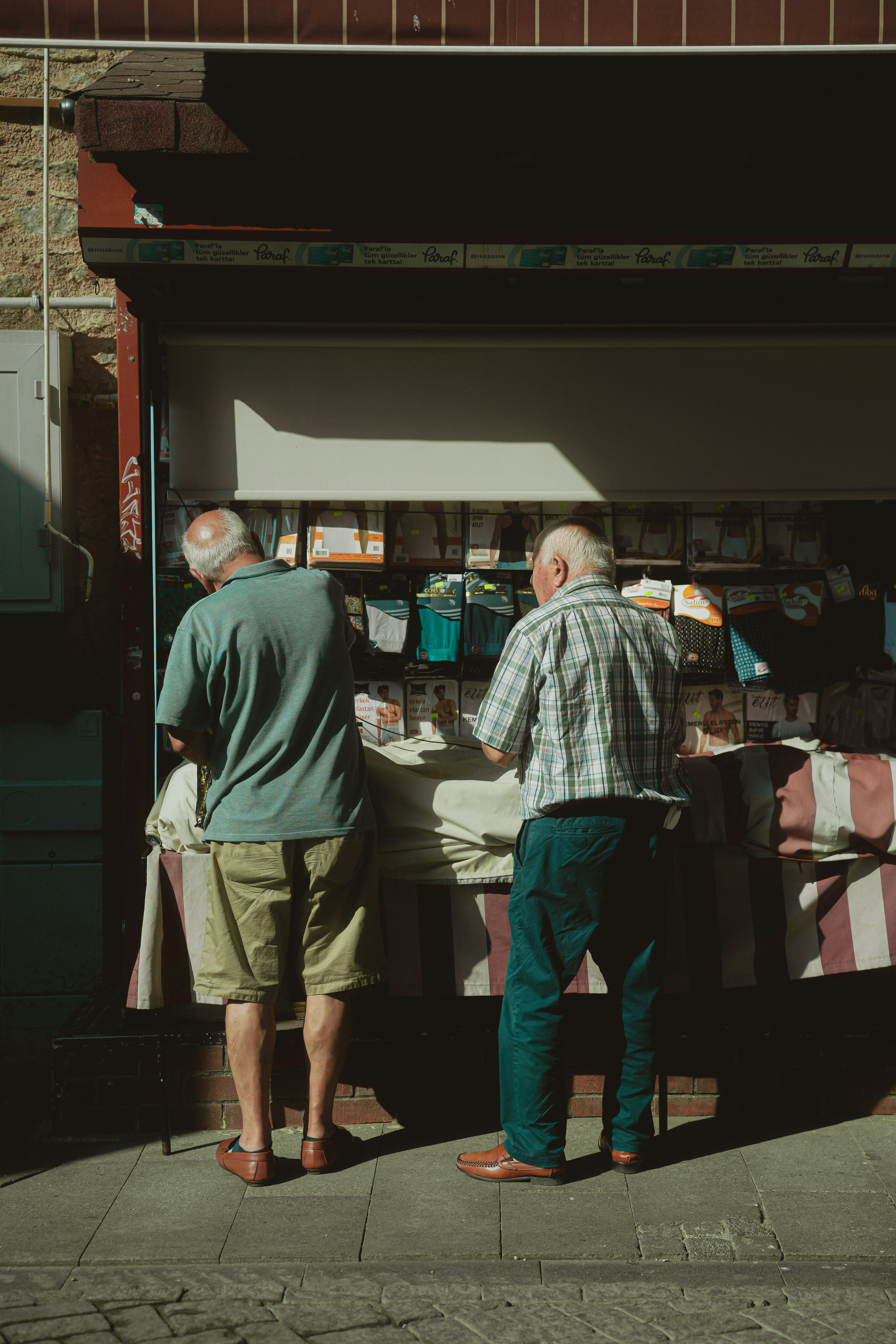 Two elderly men browse a market stall. photo – Free Purple Image on ...
